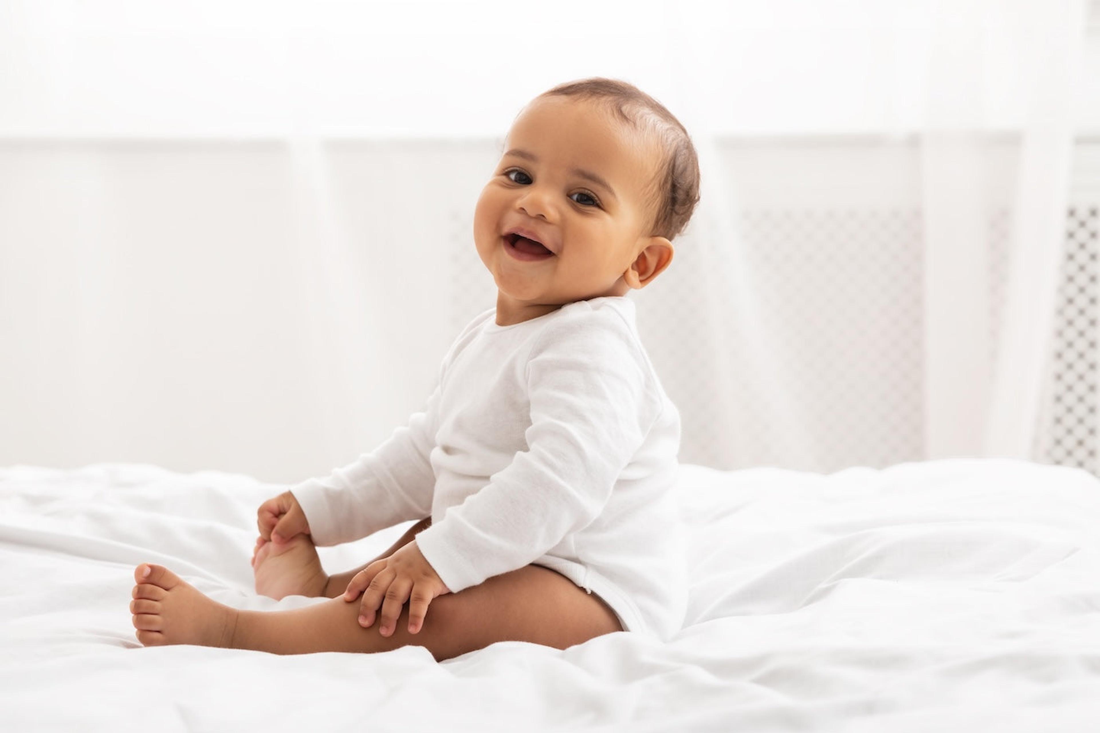 Cute baby boy sitting on a white bed
