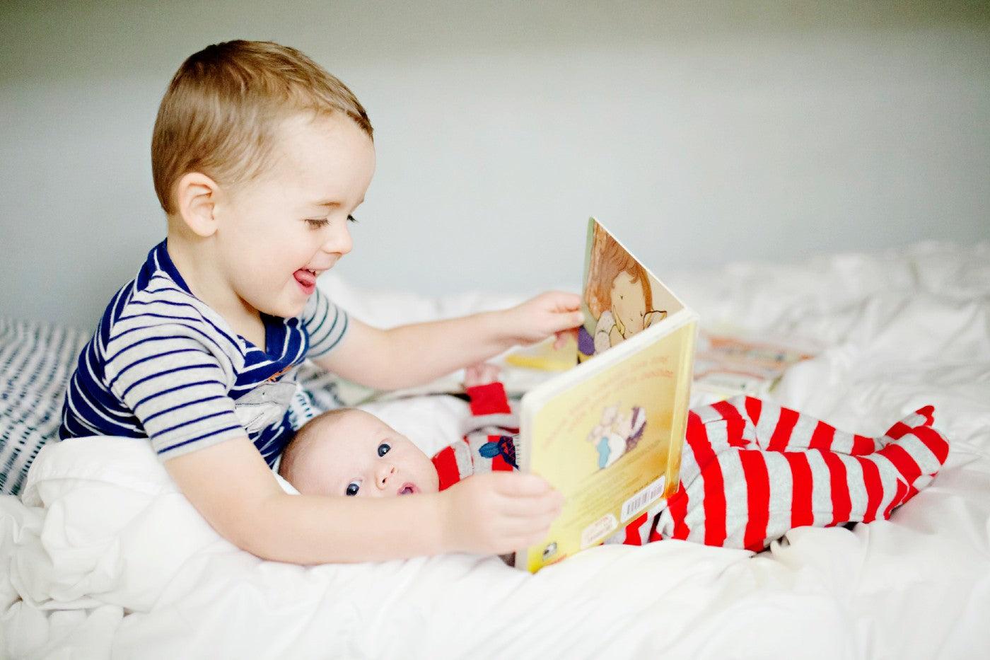 bedtime books - toddler reading in bed to baby