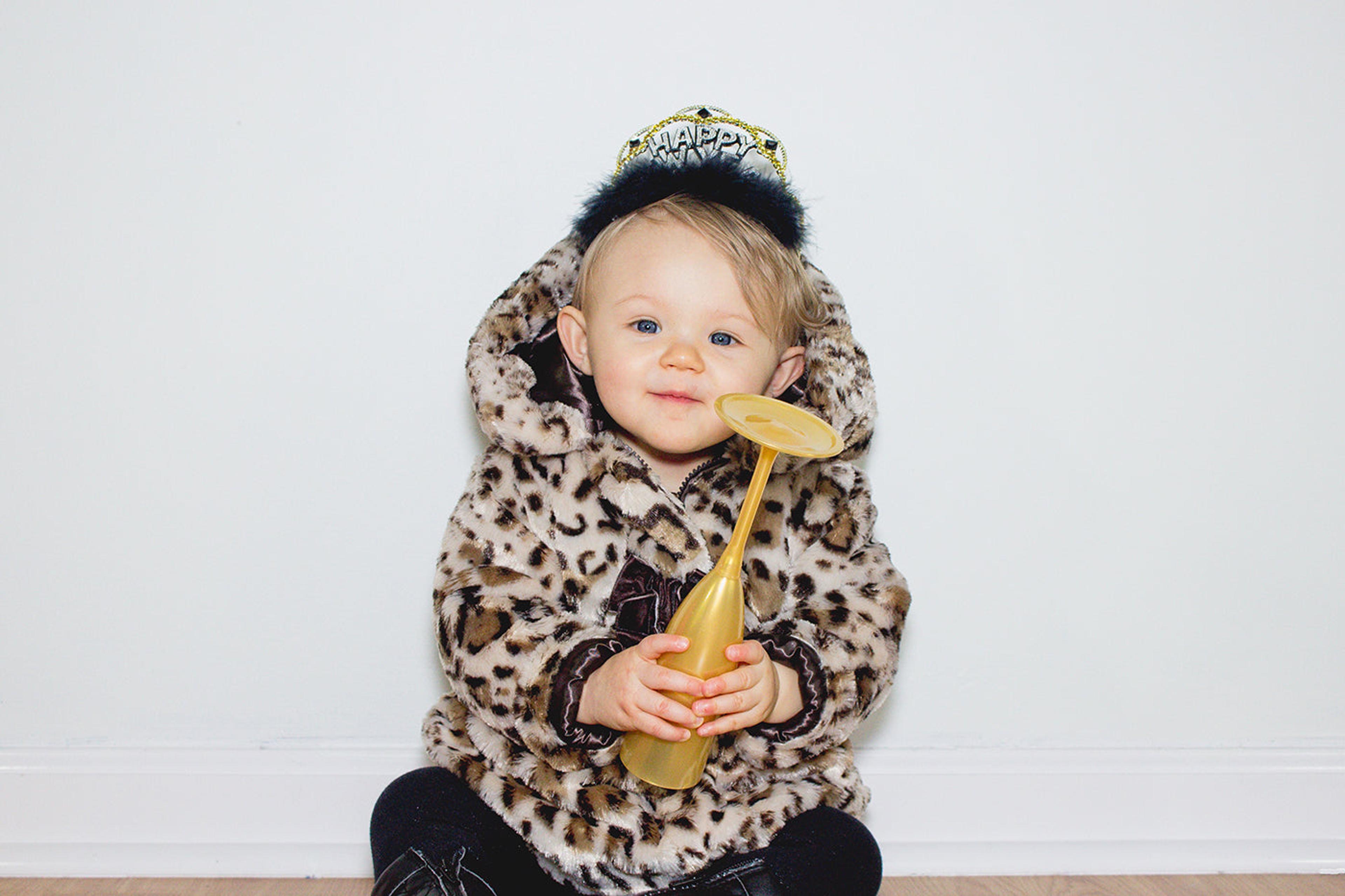 Baby with happy new year crown holding plastic champagne flute