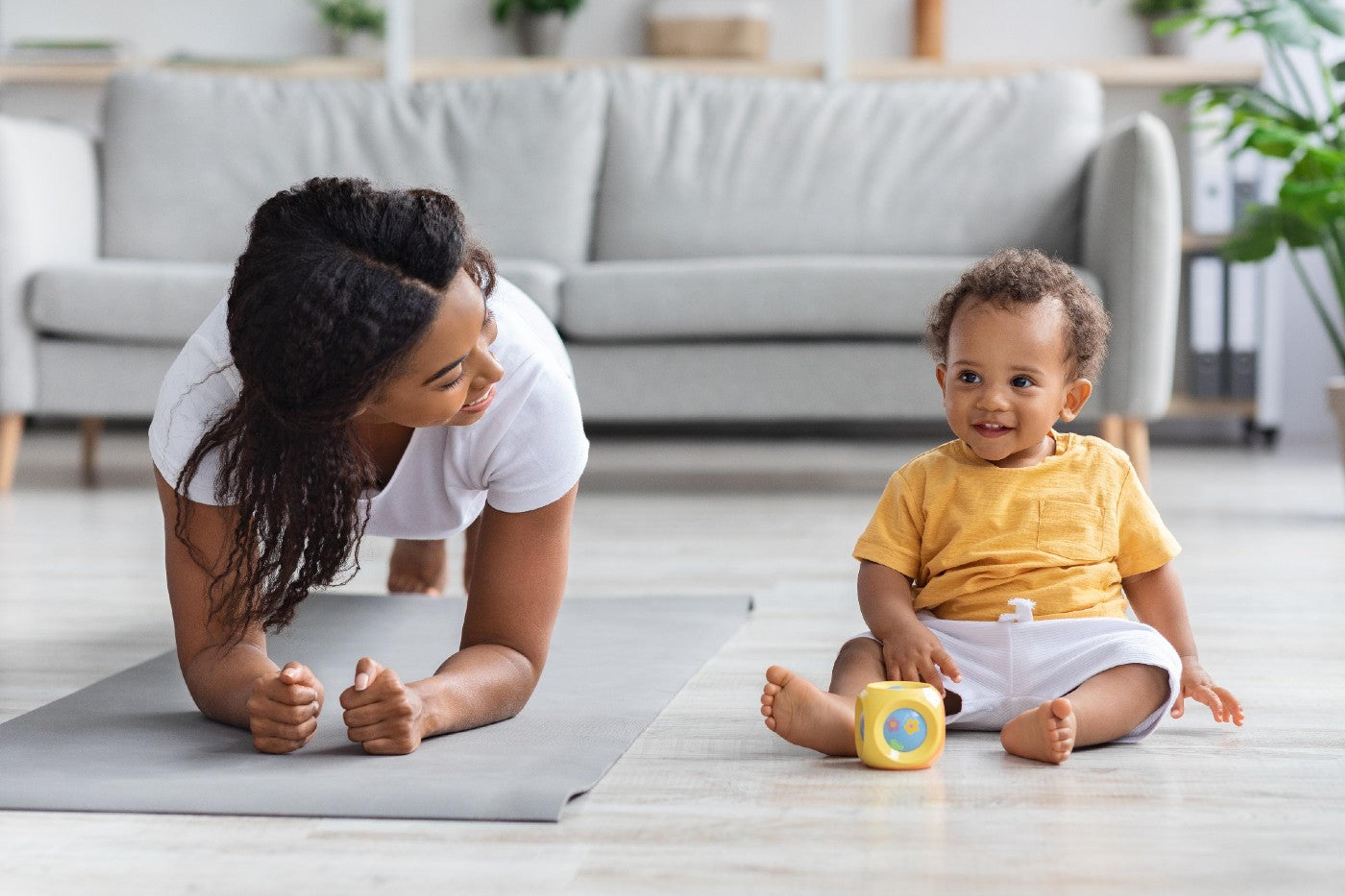 A mom holds a plank next to her seated baby