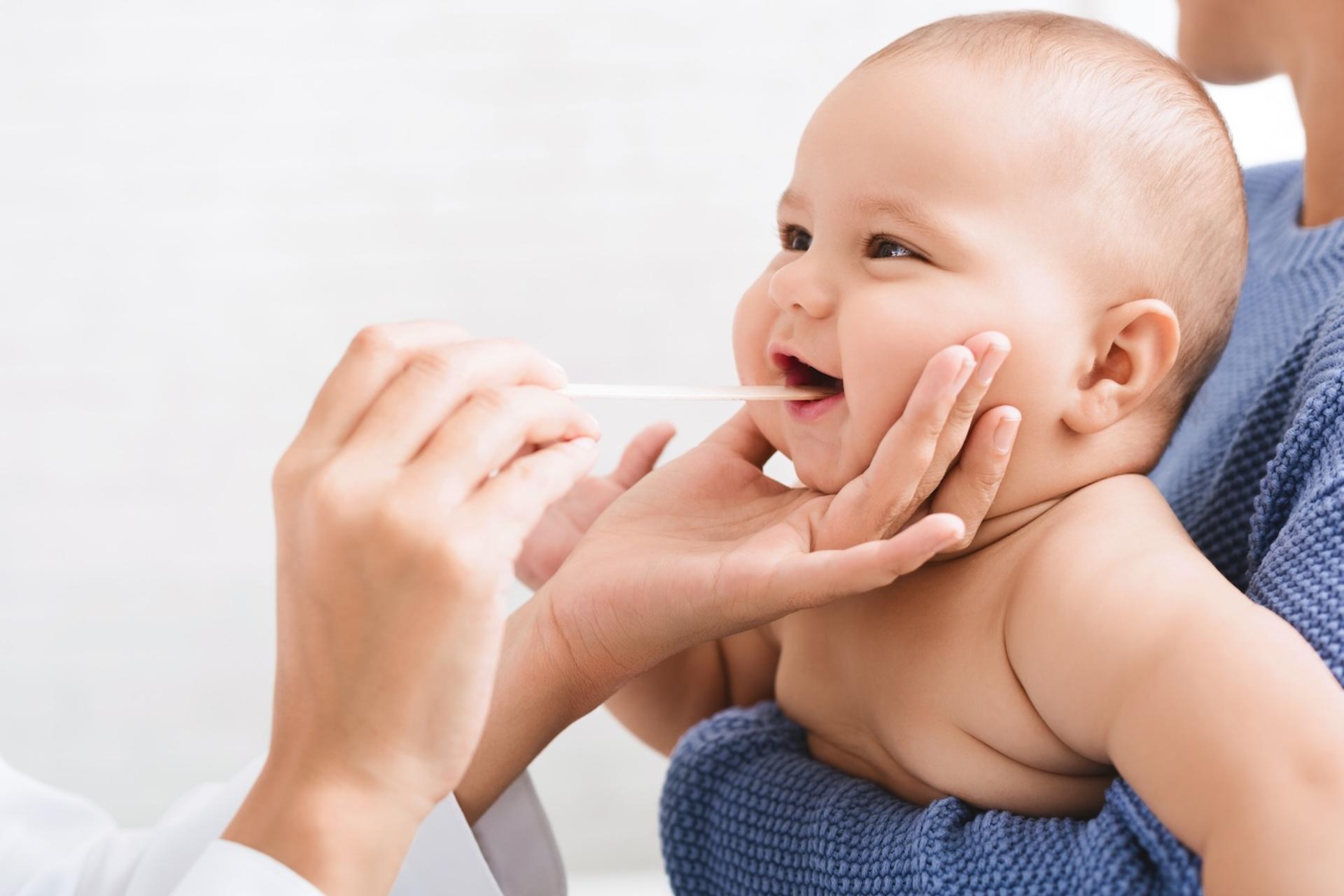 A doctor examines the inside of a baby's mouth