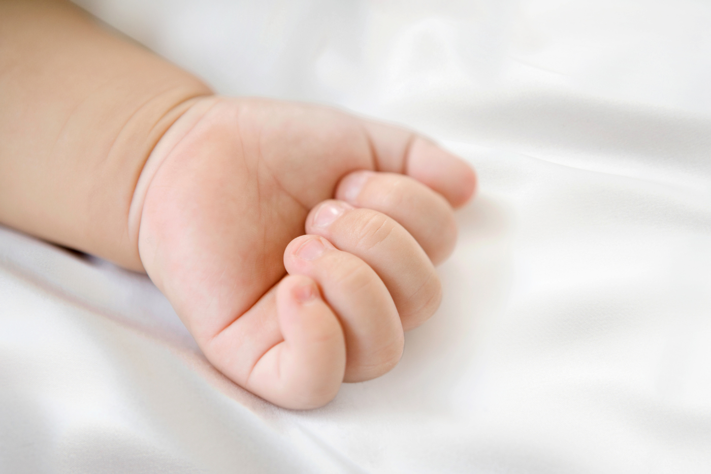 Baby's hand on SNOO silk bassinet sheet