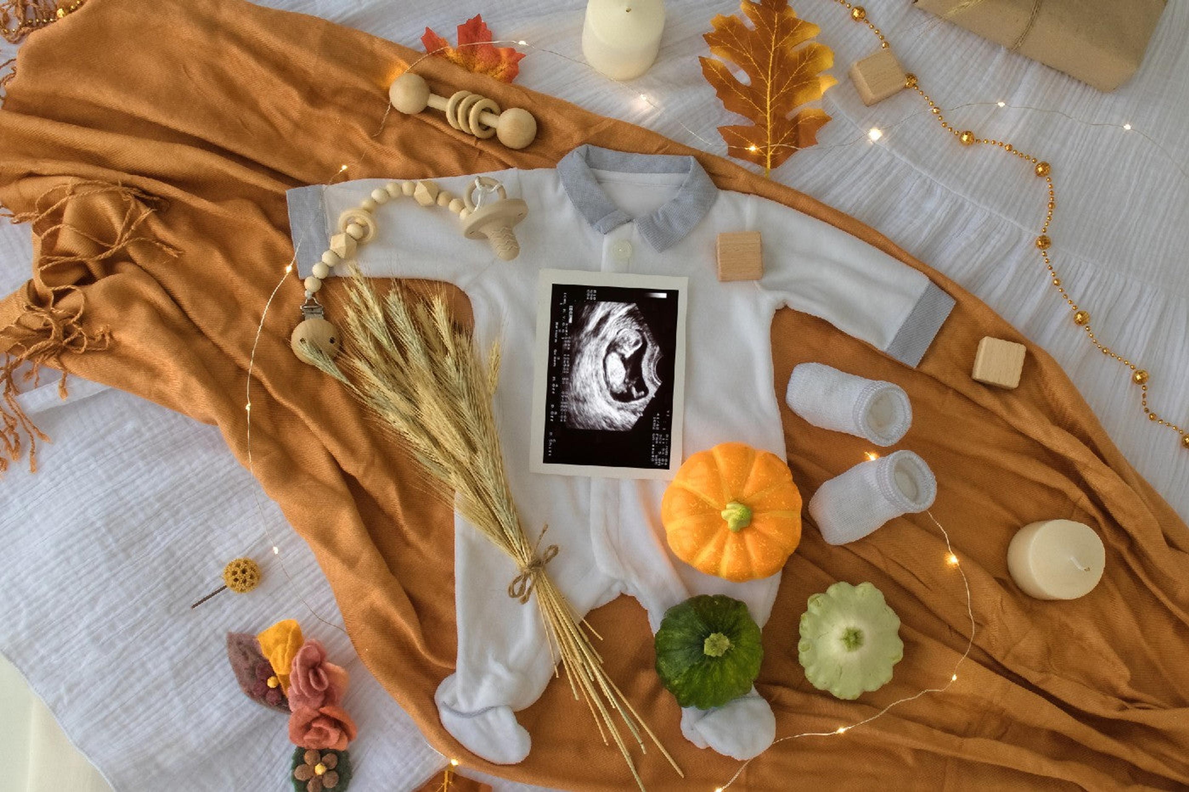 Baby outfit and ultrasound displayed with fall decor
