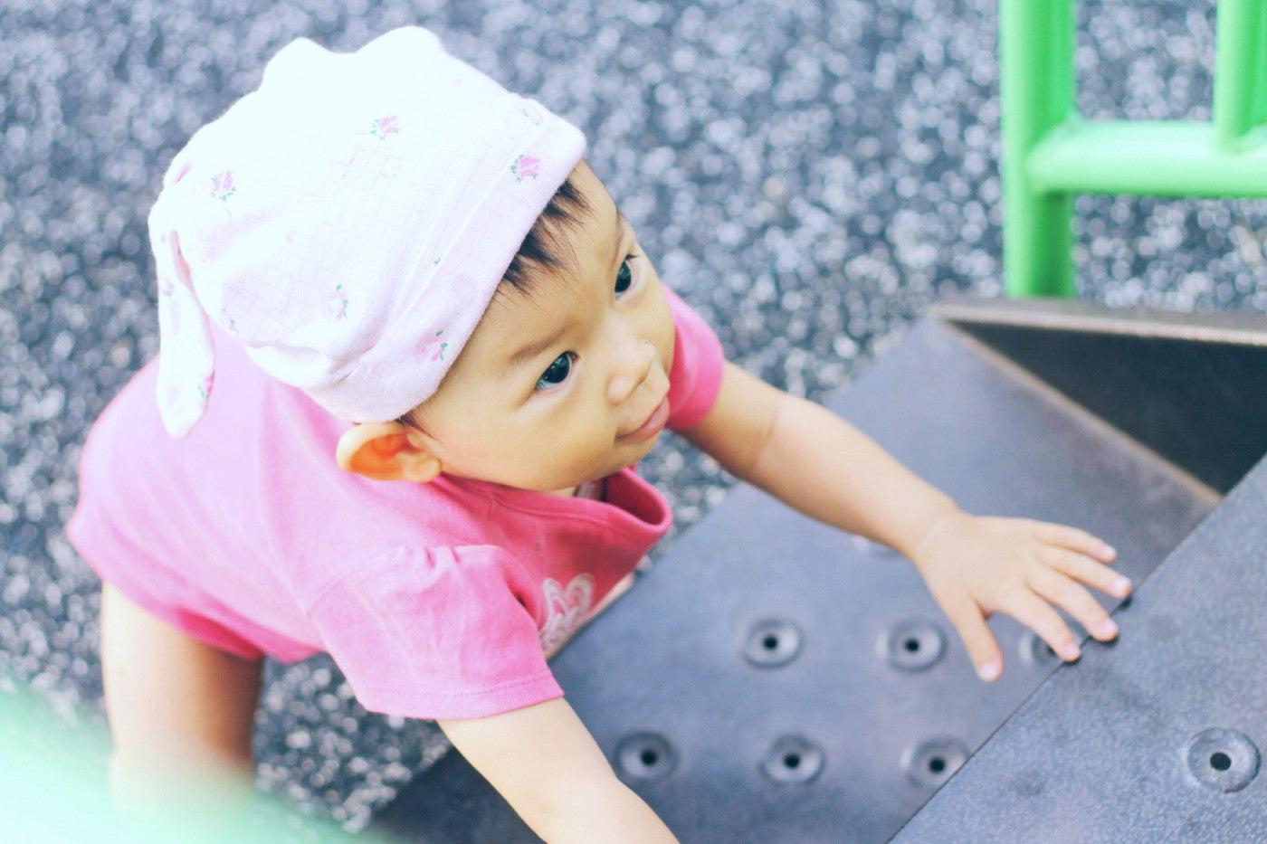 Baby girl climbs up playground steps