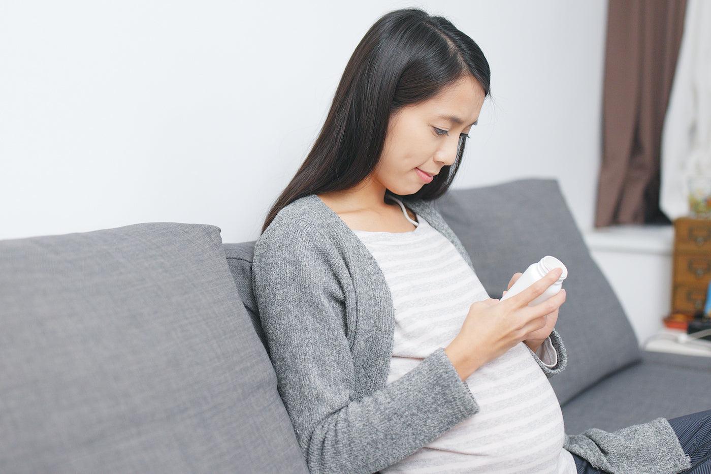 A pregnant woman reviews the contents of her prenatal vitamin for folic acid content
