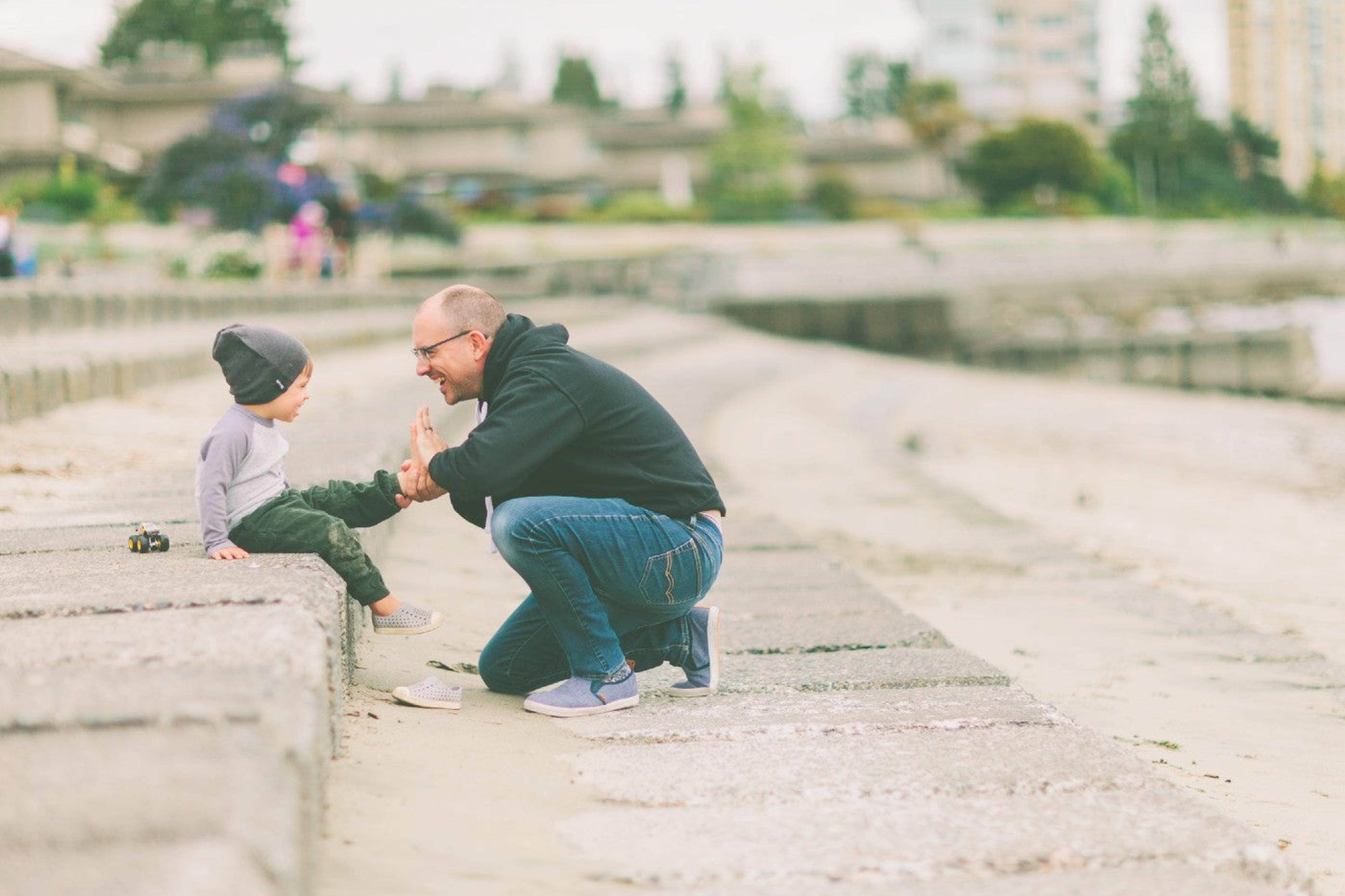 Father putting on toddler son's shoes at the beach. 