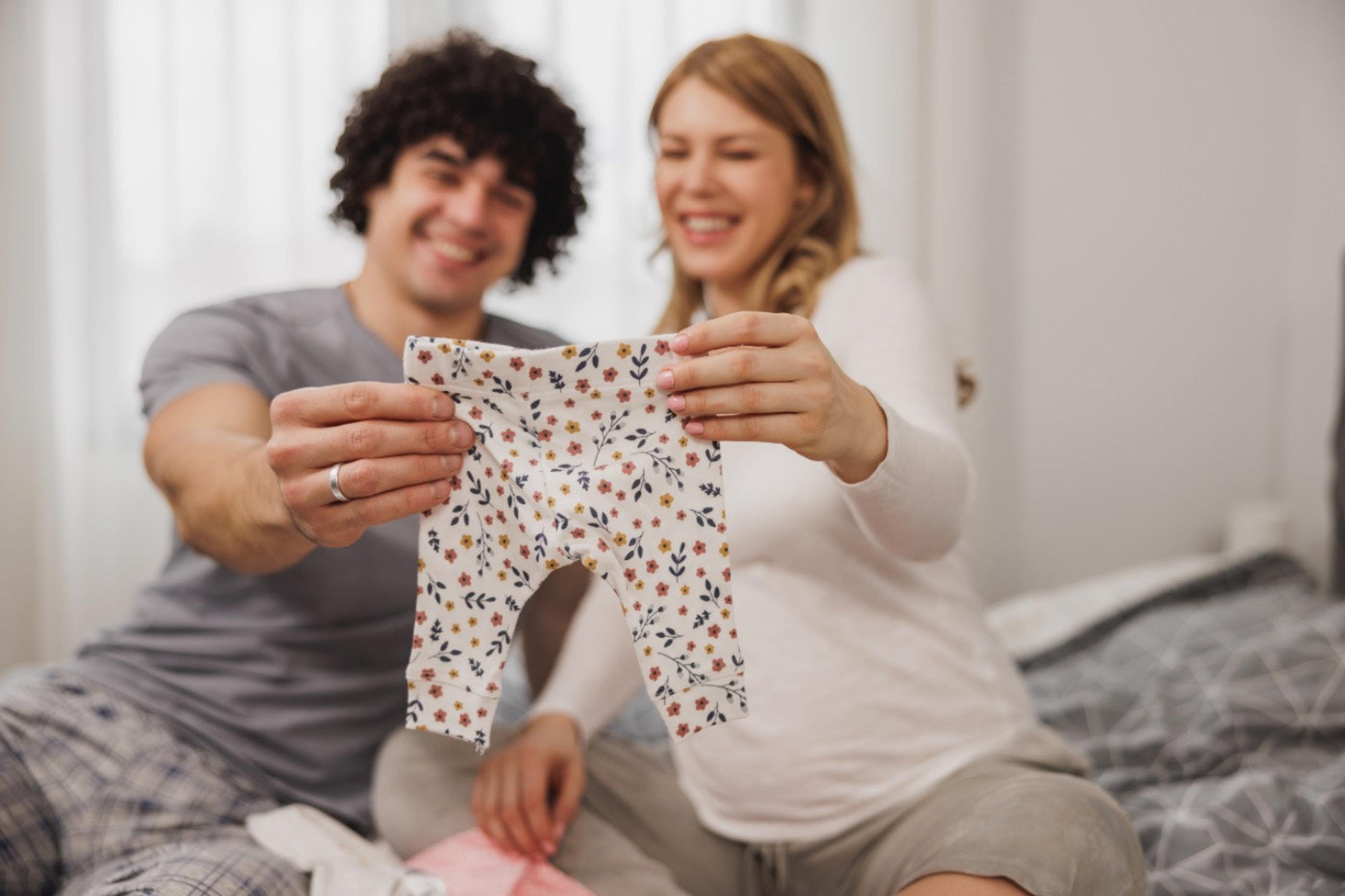 overlooked baby items: couple holding up soft baby pants