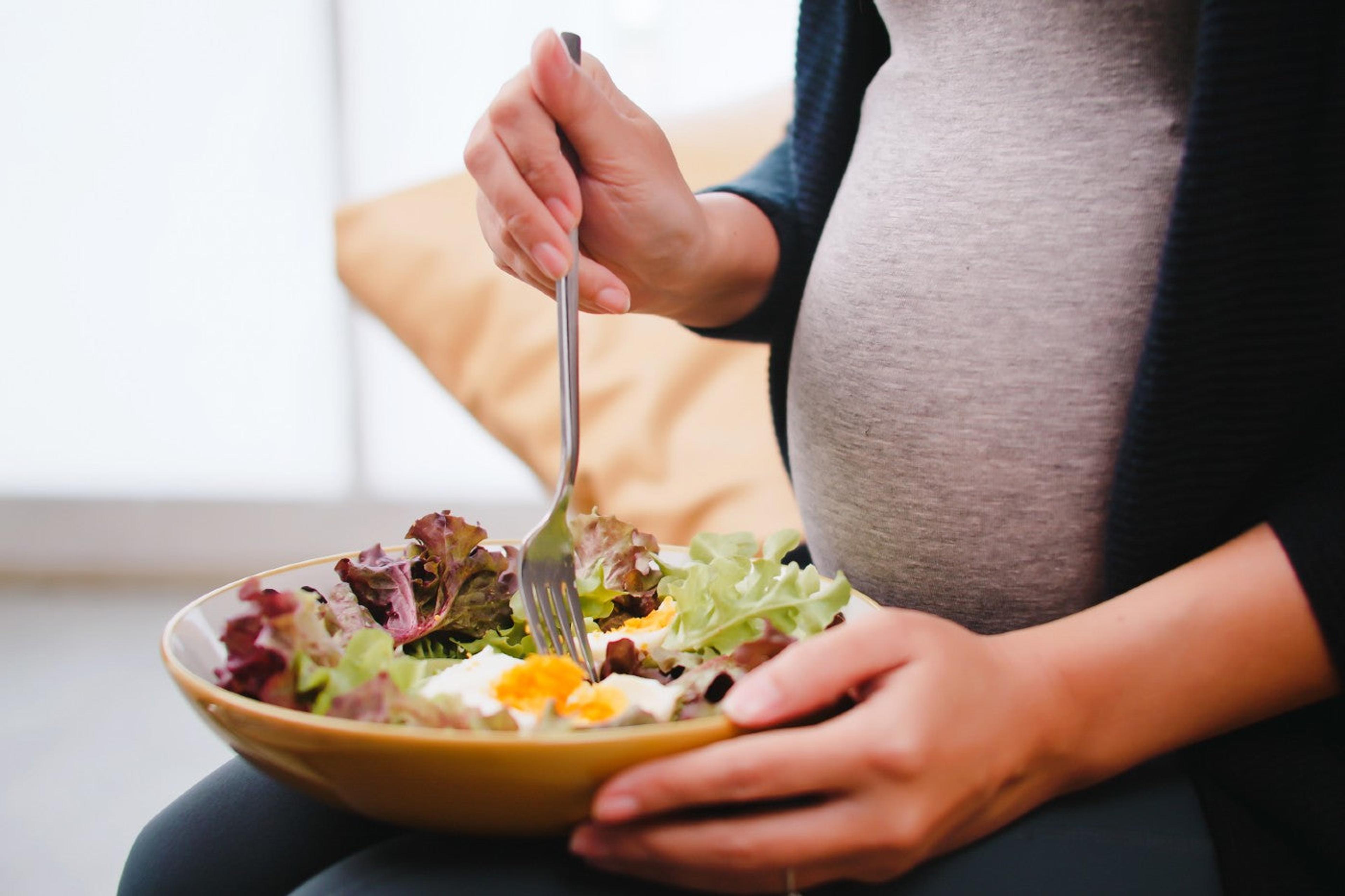 A pregnant person eats a vegetable salad