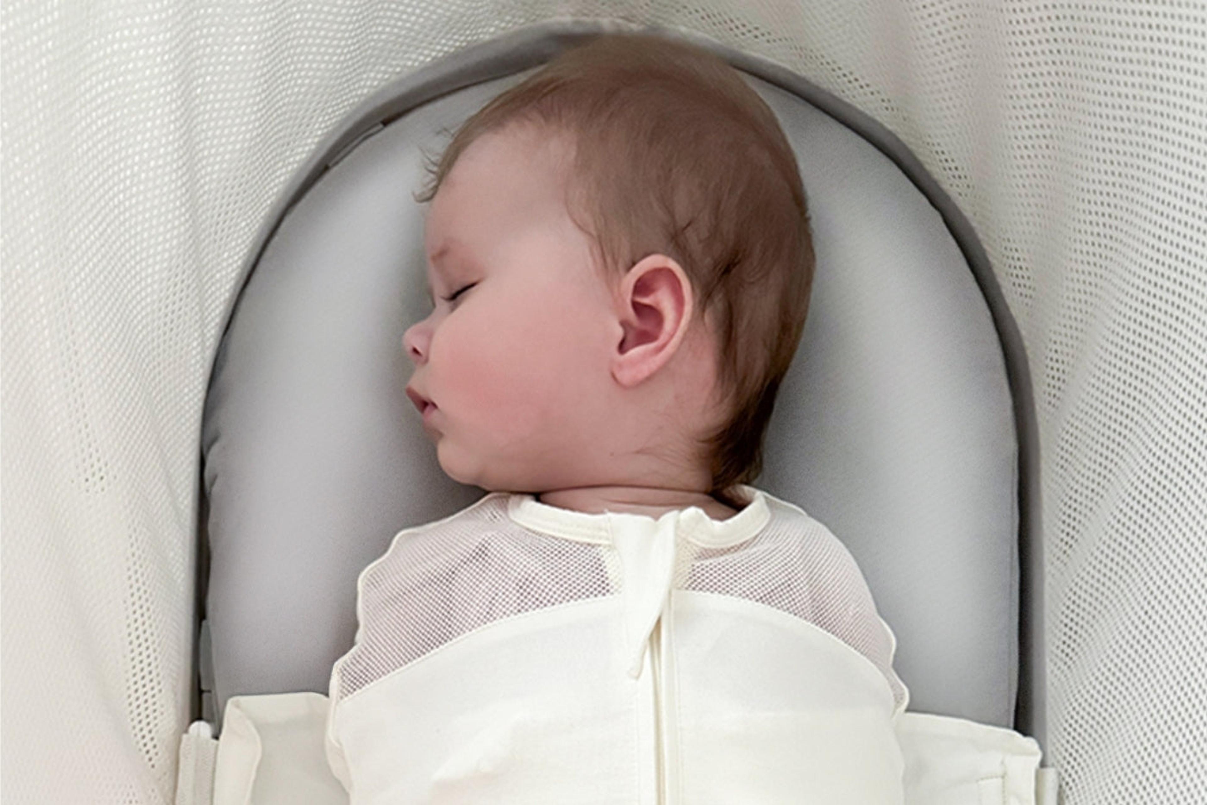 A baby sleeps on a silk bassinet sheet inside SNOO