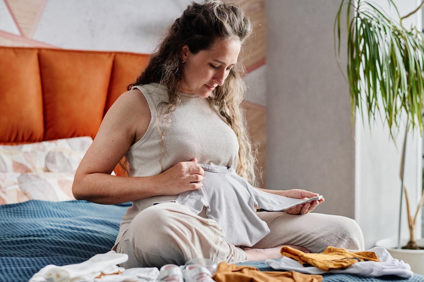 An expecting mom folds baby clothes