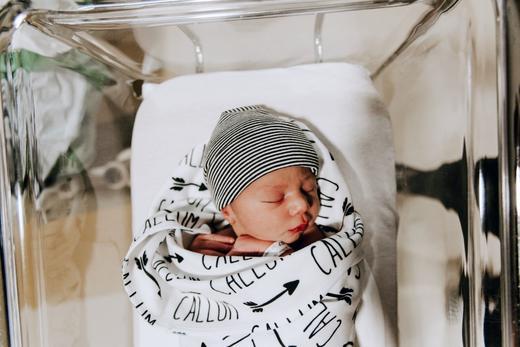 A swaddled newborn sleeps in the hospital