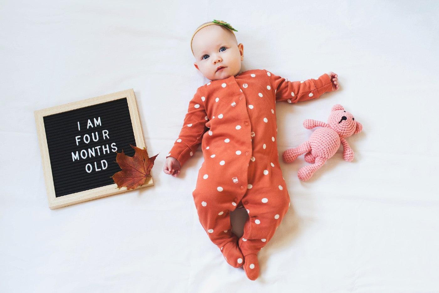 Baby posing with letter board that says "I am four months old"