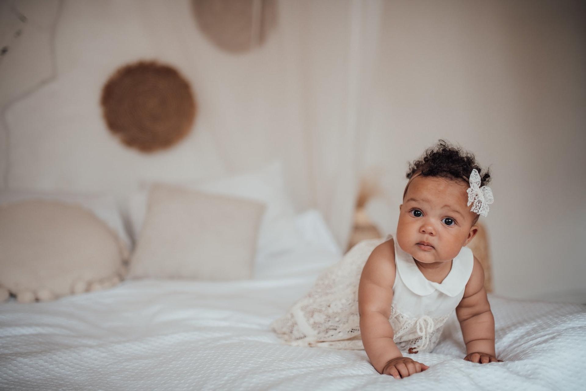 Baby girl dressed in white on a bed