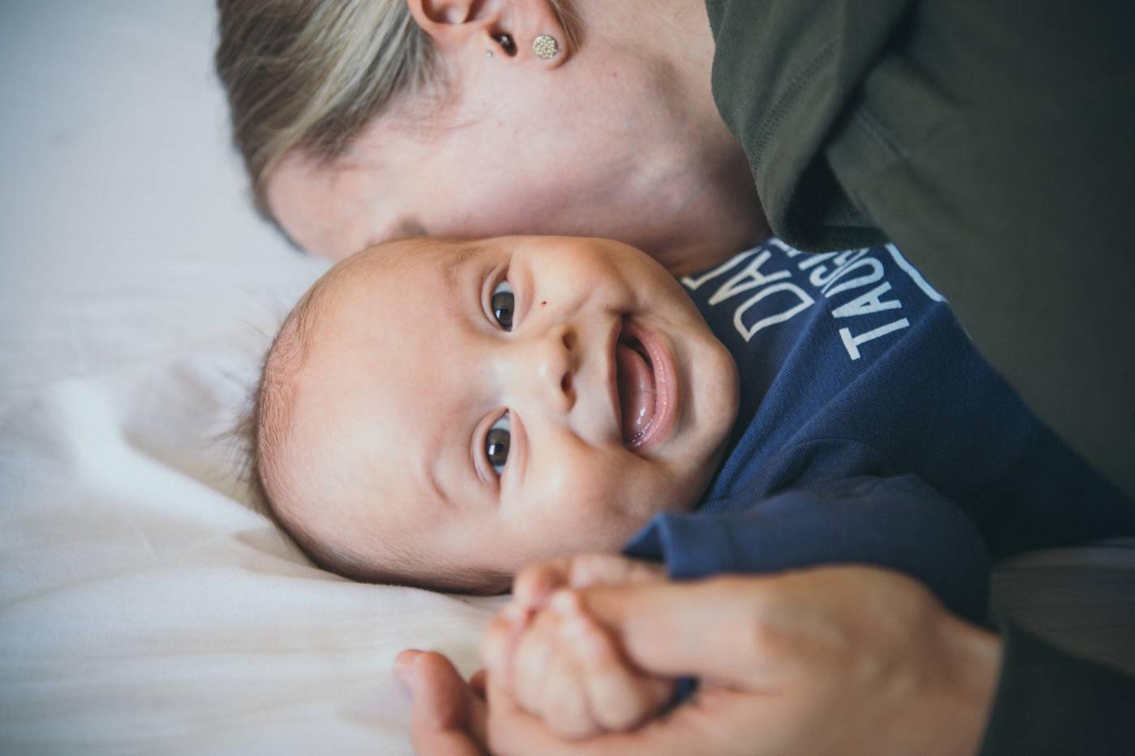 A mom kisses her baby's cheek.