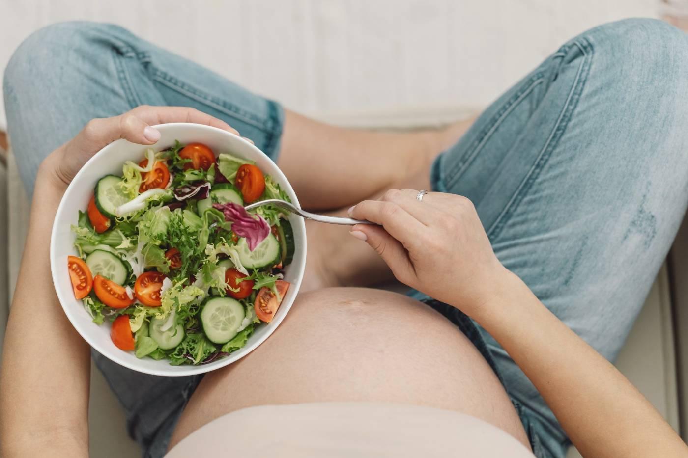 Pregnant woman holding salad in her lap