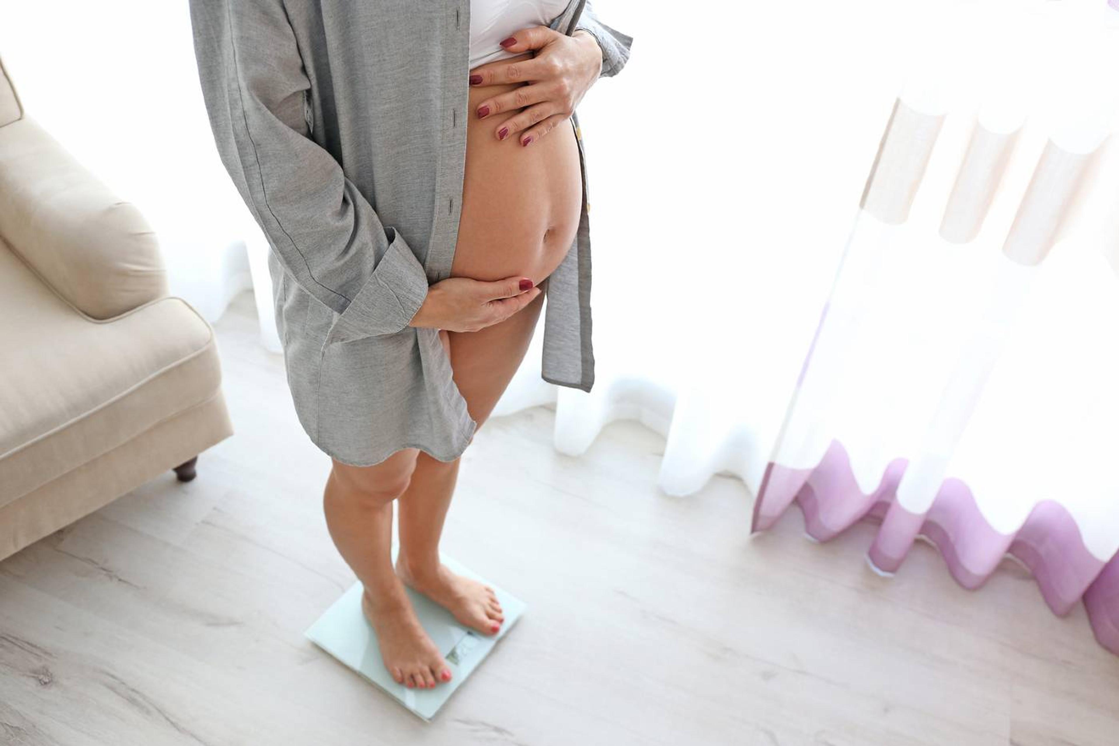 Pregnant person on scale weighing themselves