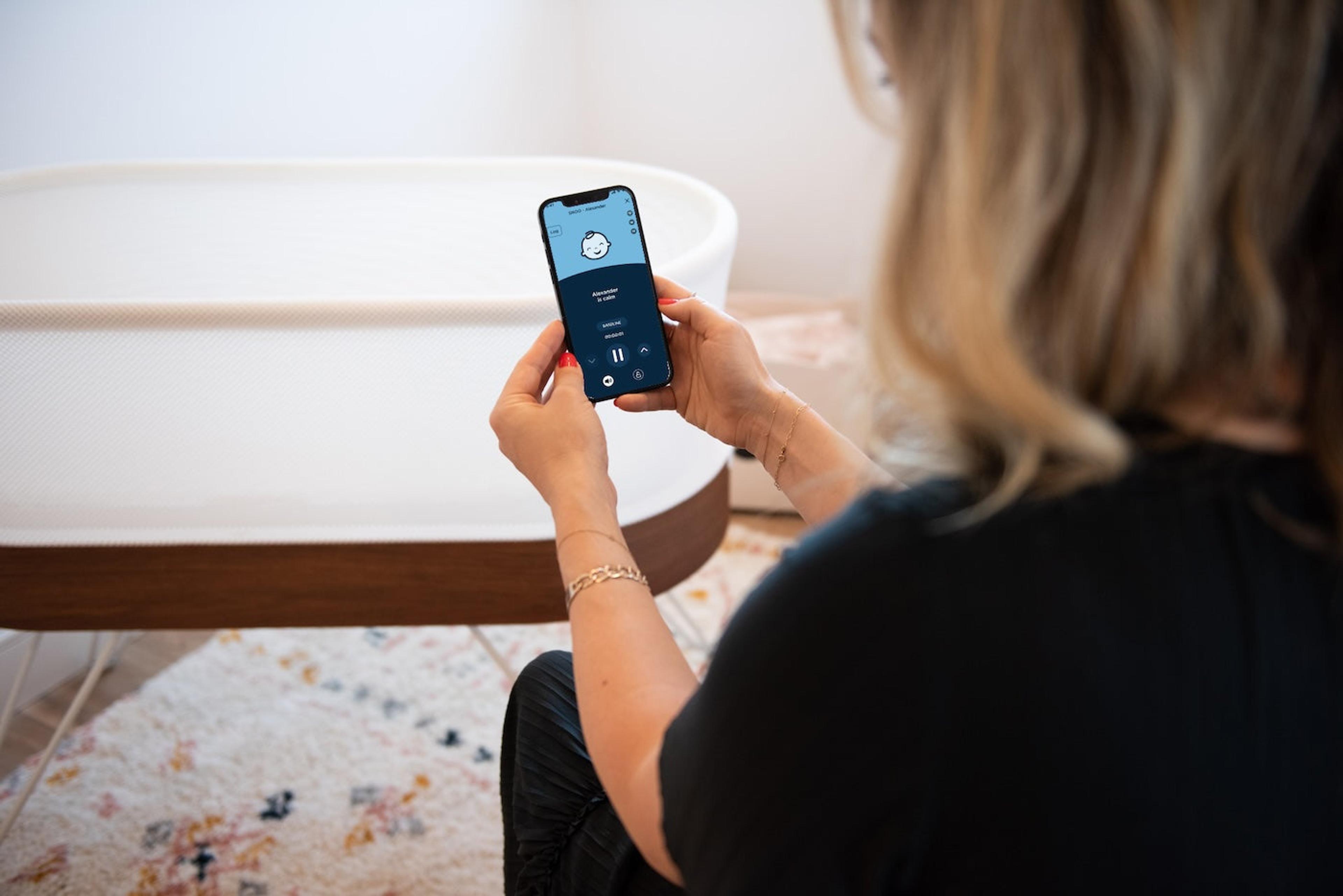 A mom uses the Happiest Baby premium app to control her SNOO