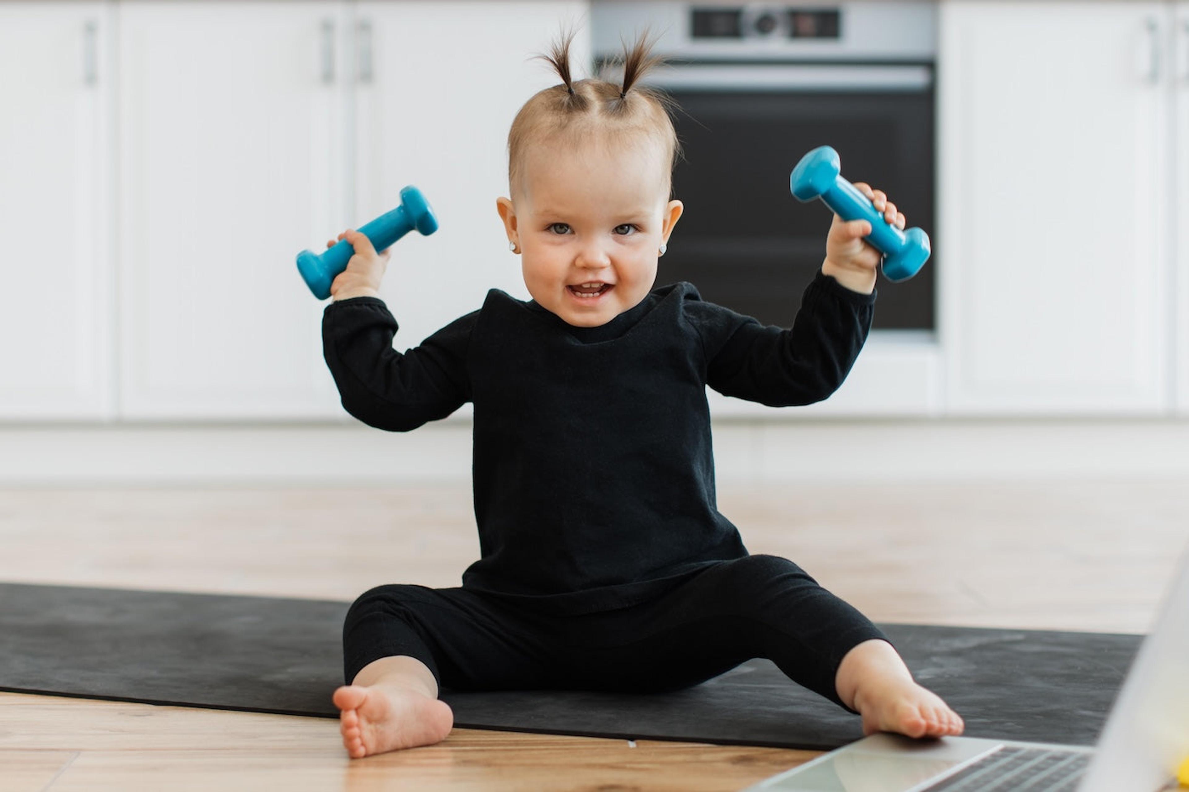 Baby girl holding dumbbells 