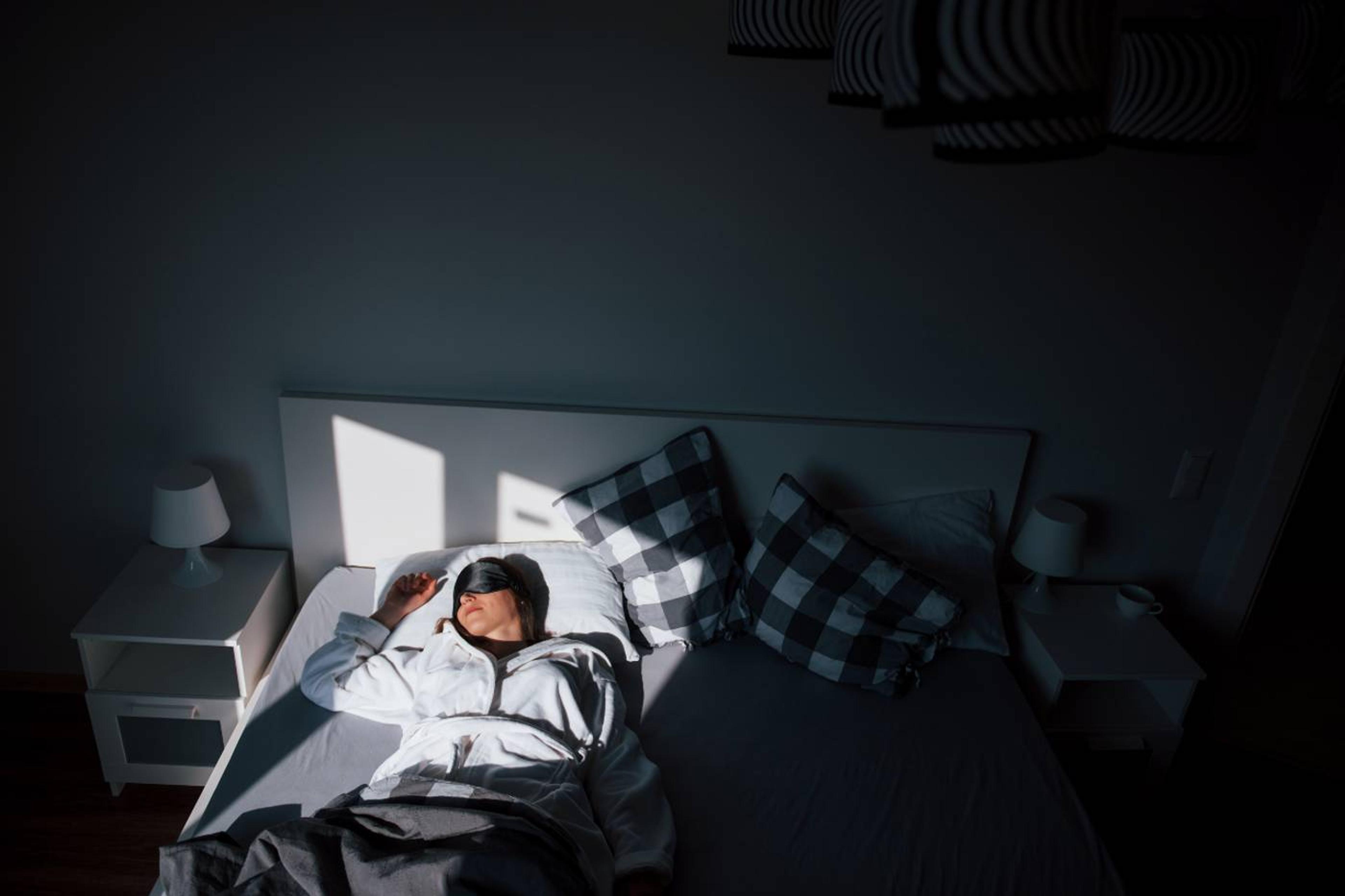 How light and darkness impact sleep: woman sleeping with a stream of sunlight on her