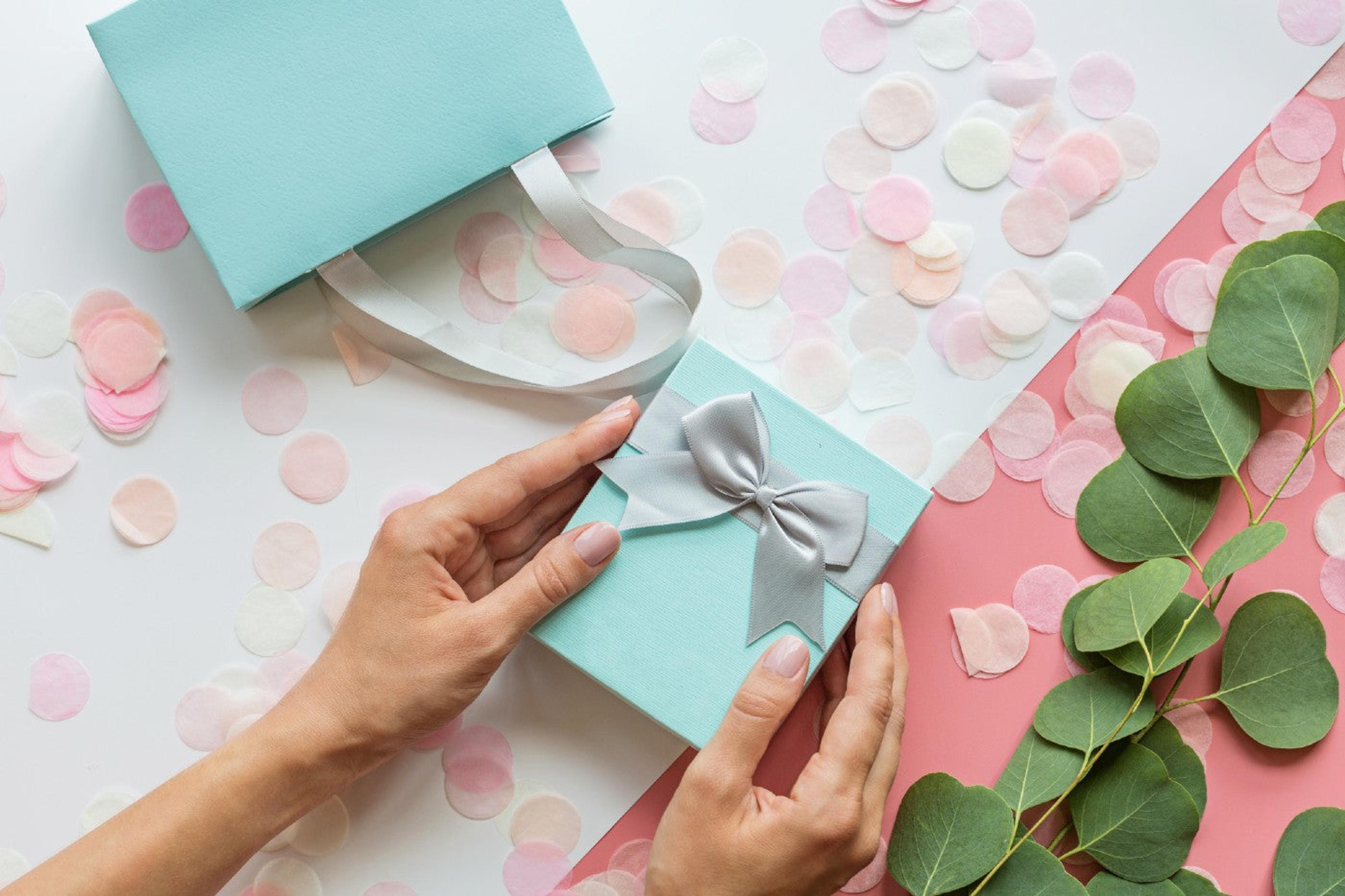 Hands hold a blue wrapped pregnancy announcement gift
