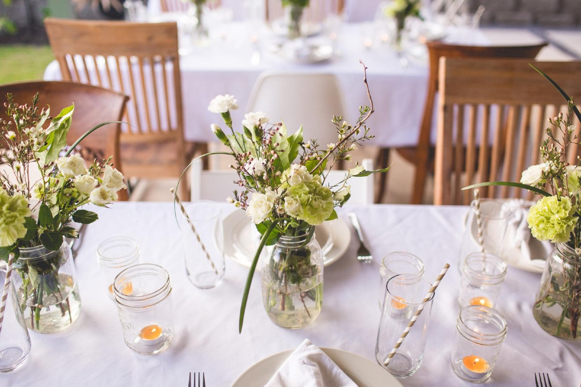 Outdoor table decorated with flowers and mason jars for a summer baby shower