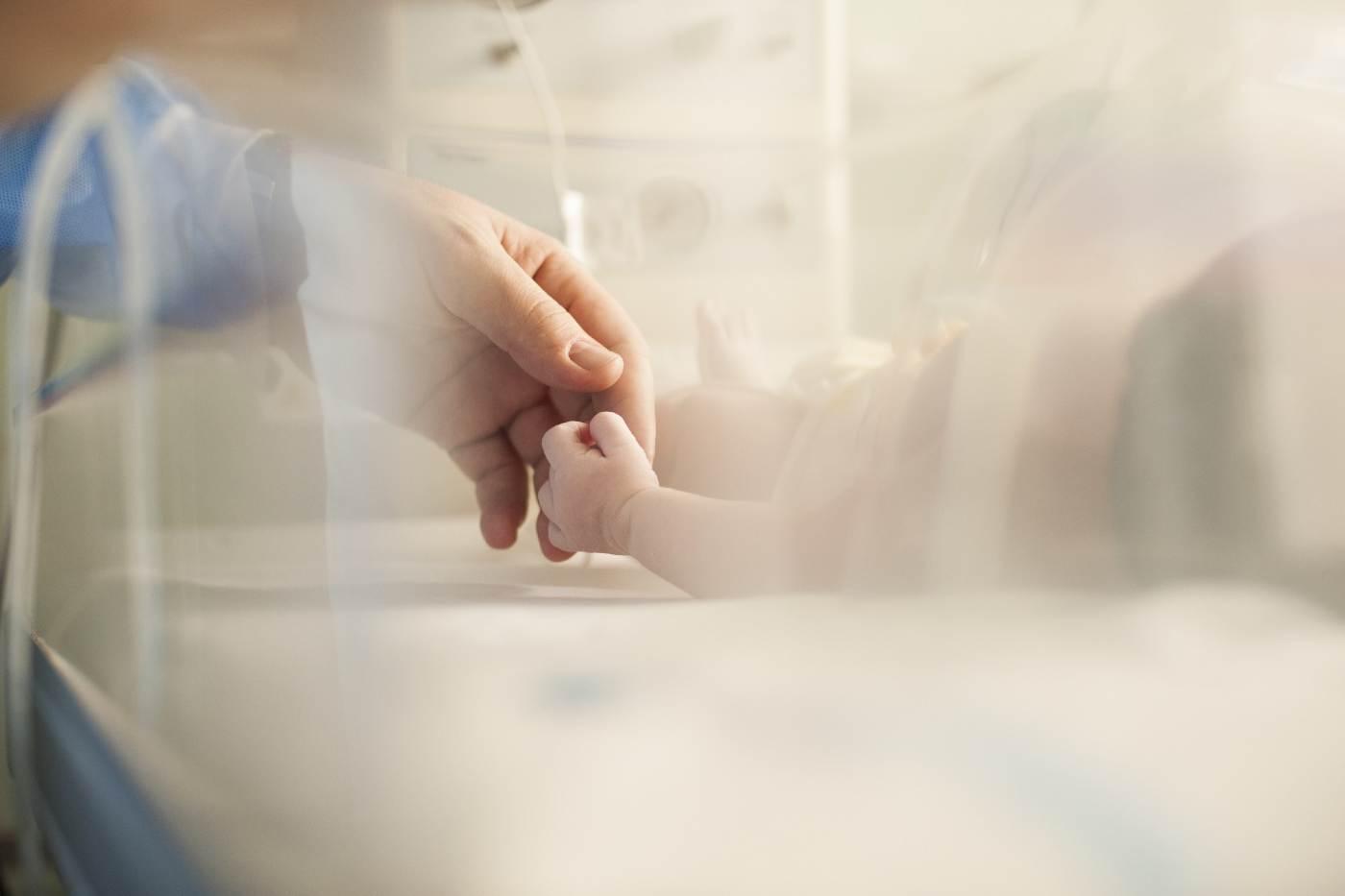 Preemie gifts: Father holding newborn hand in NICU
