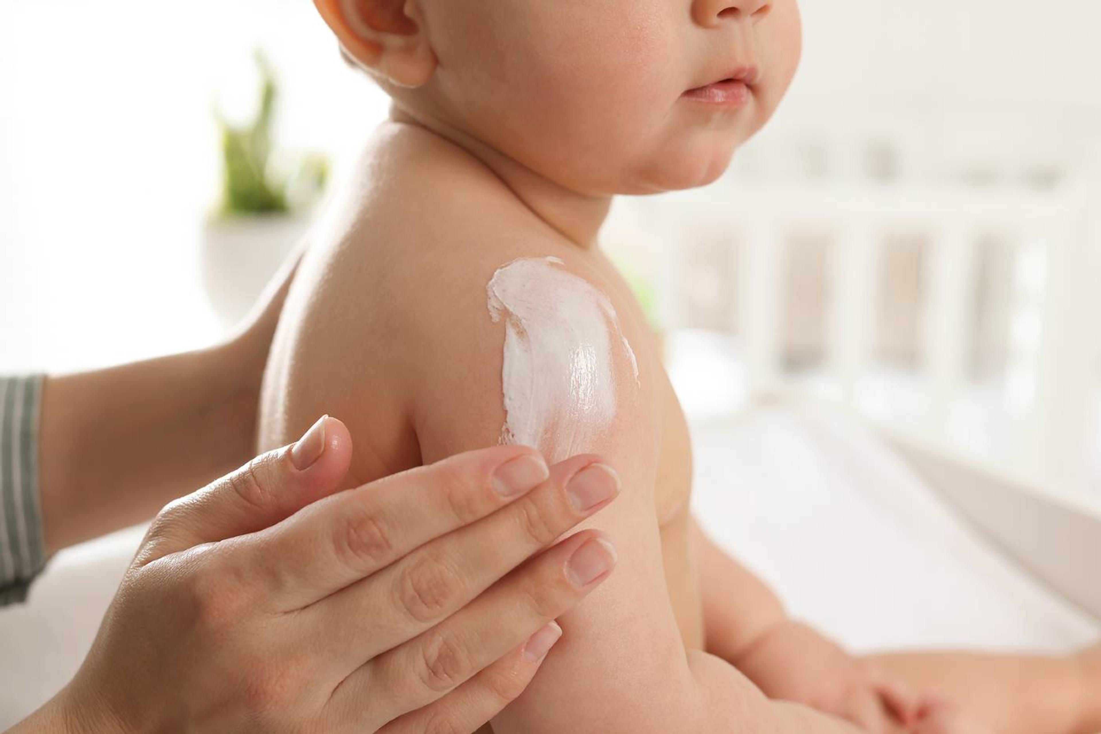 Parent applying baby lotion to Baby