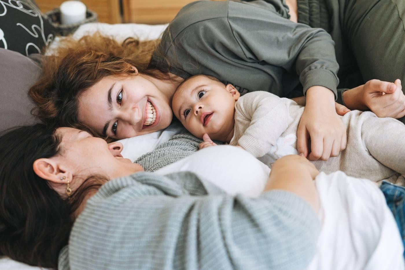 Two woman and a baby snuggling in bed