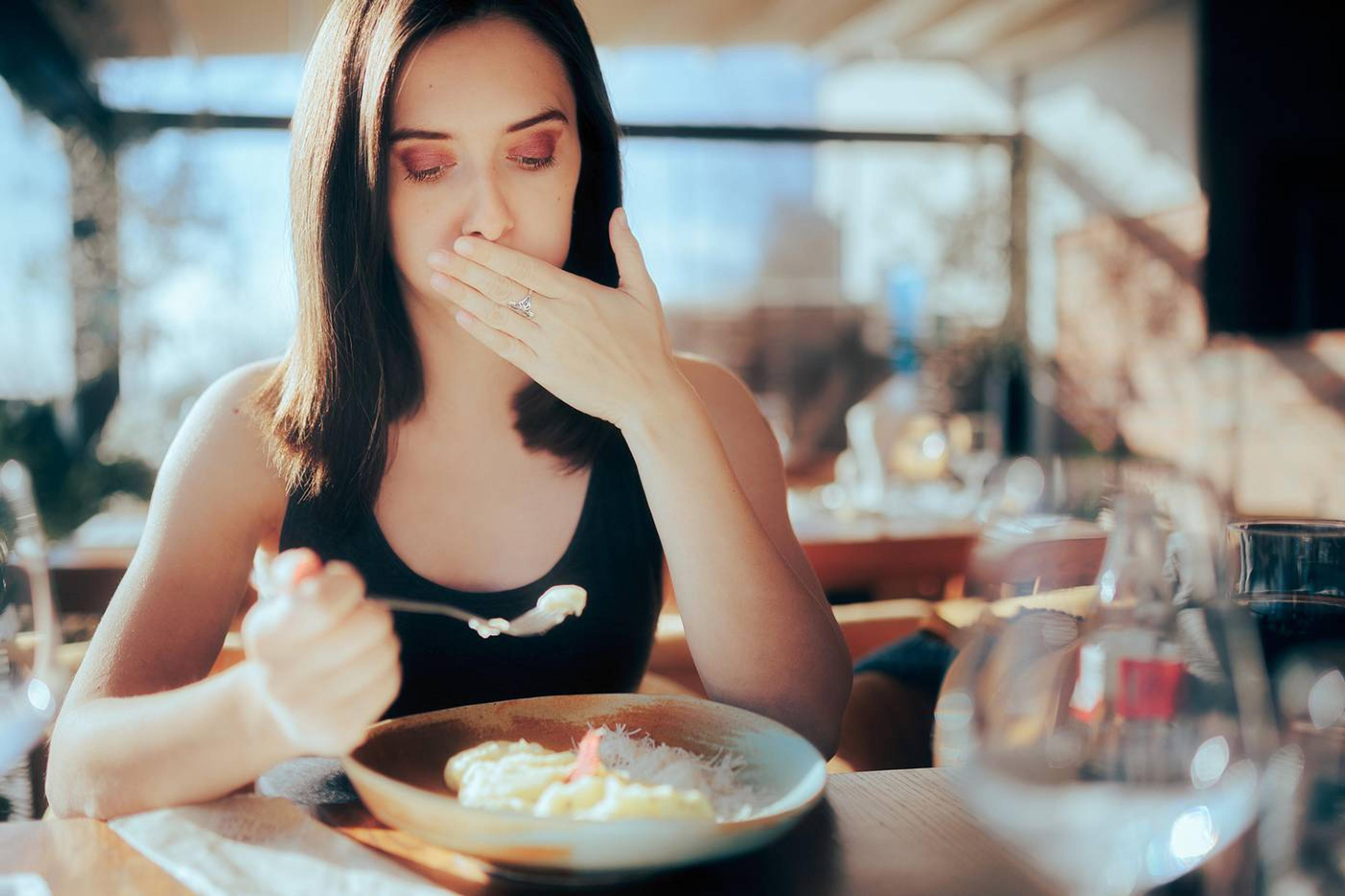 Early pregnancy signs: Woman out to eat experiencing food aversion