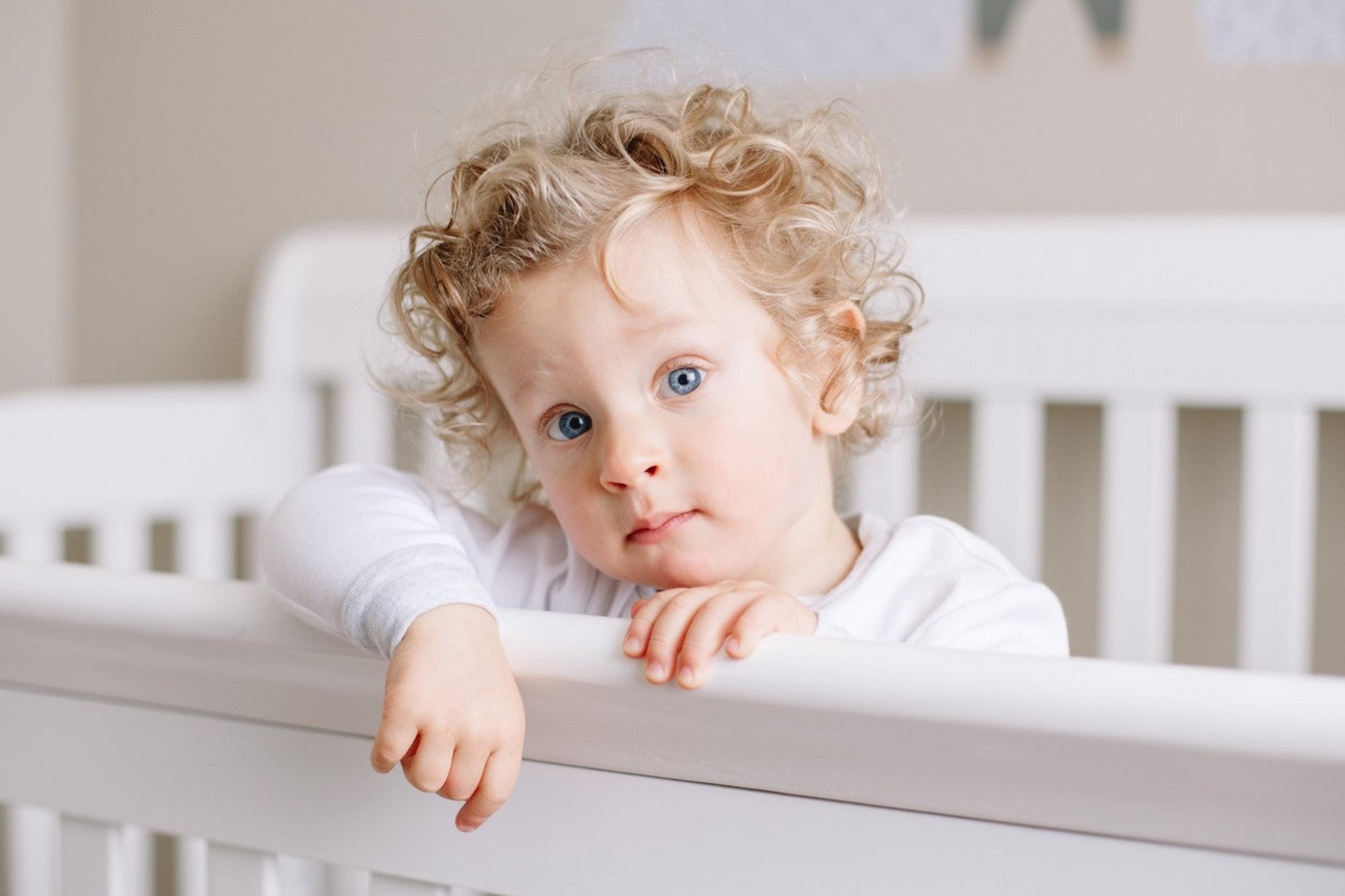 A 23-month-old baby stands in a crib