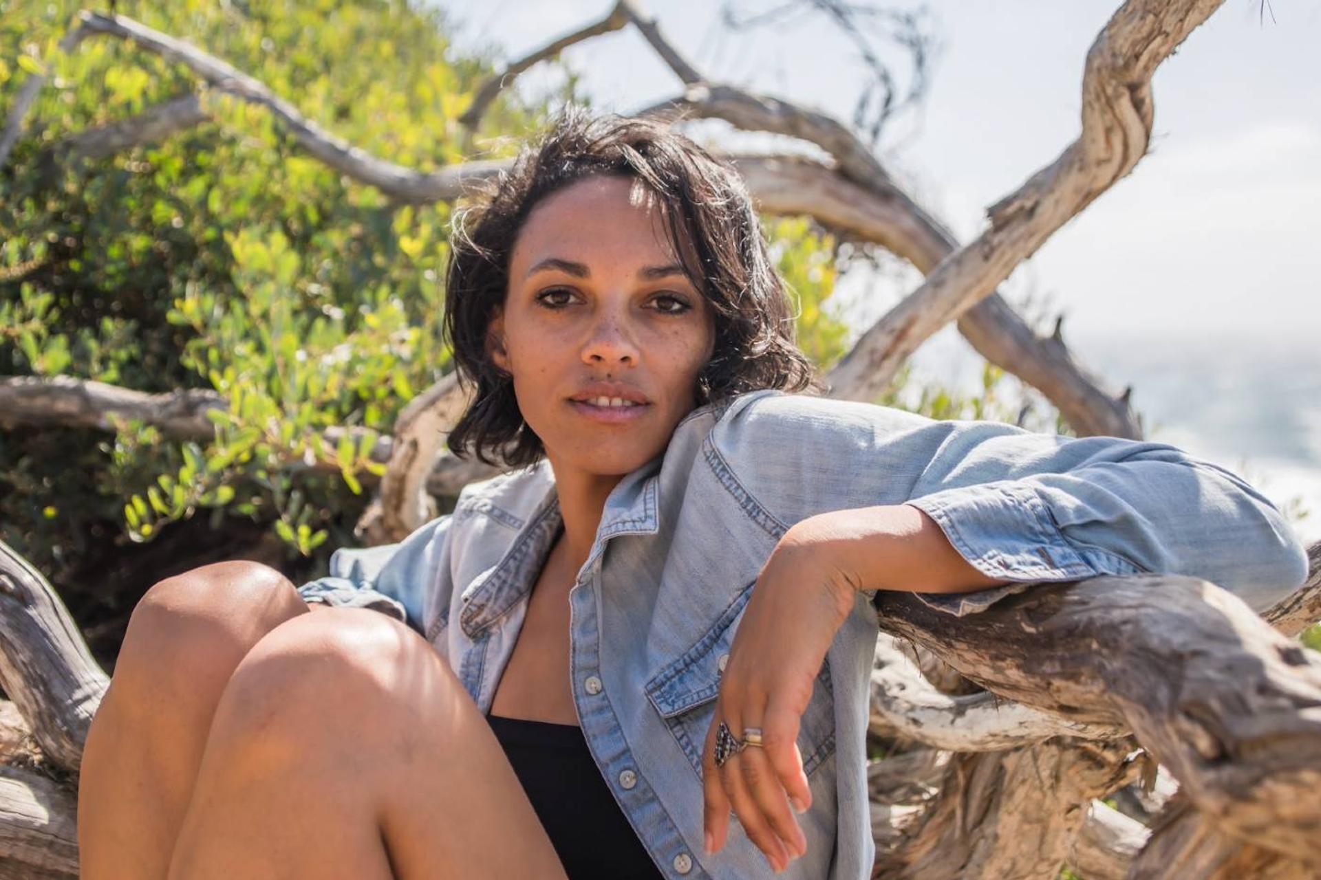 a woman on the beach sitting in drift wood