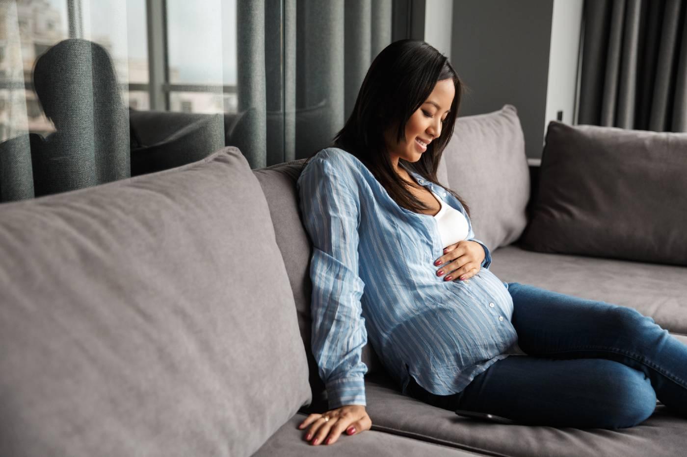Mom-to-be counting baby kicks on sofa