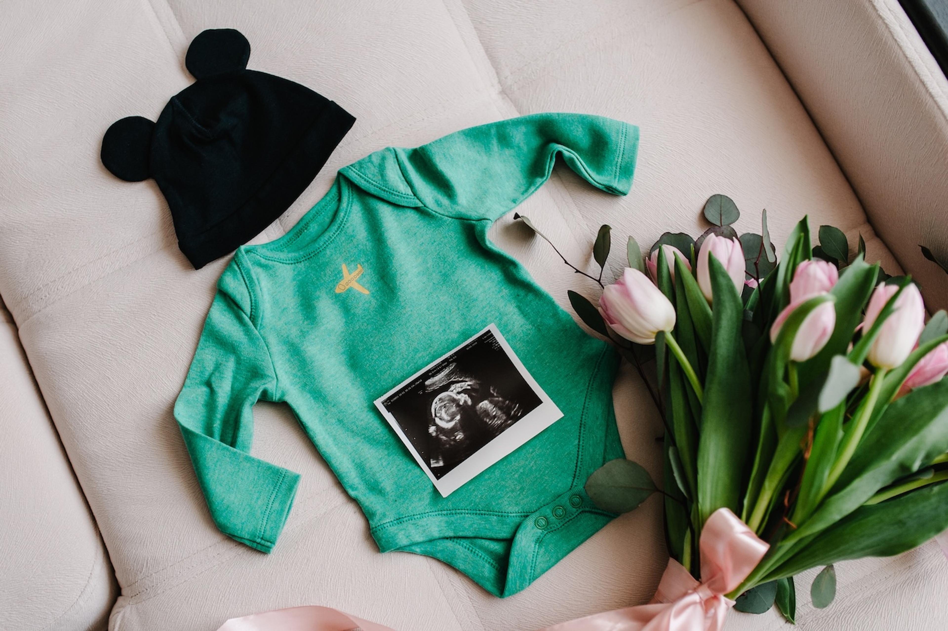 Disney-inspired pregnancy announcement with ultrasound, onesie, and mouse-ear beanie