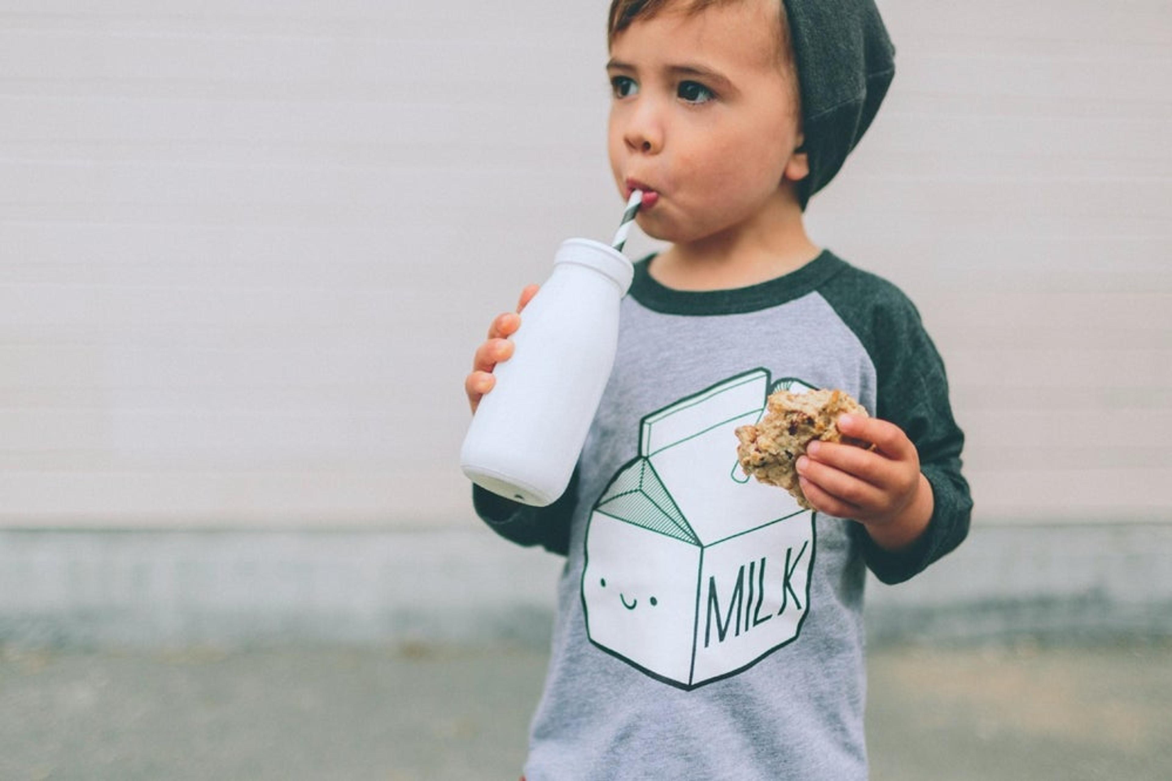 Toddler drinks milk while wearing a shirt that says "milk"