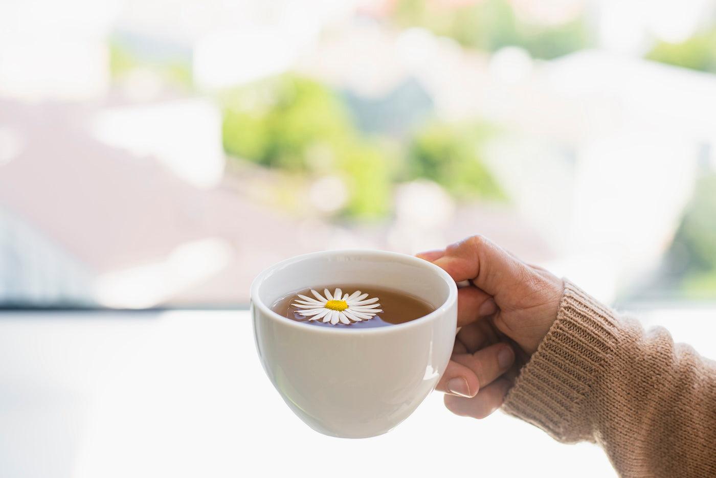 A woman holds a cup of chamomile tea