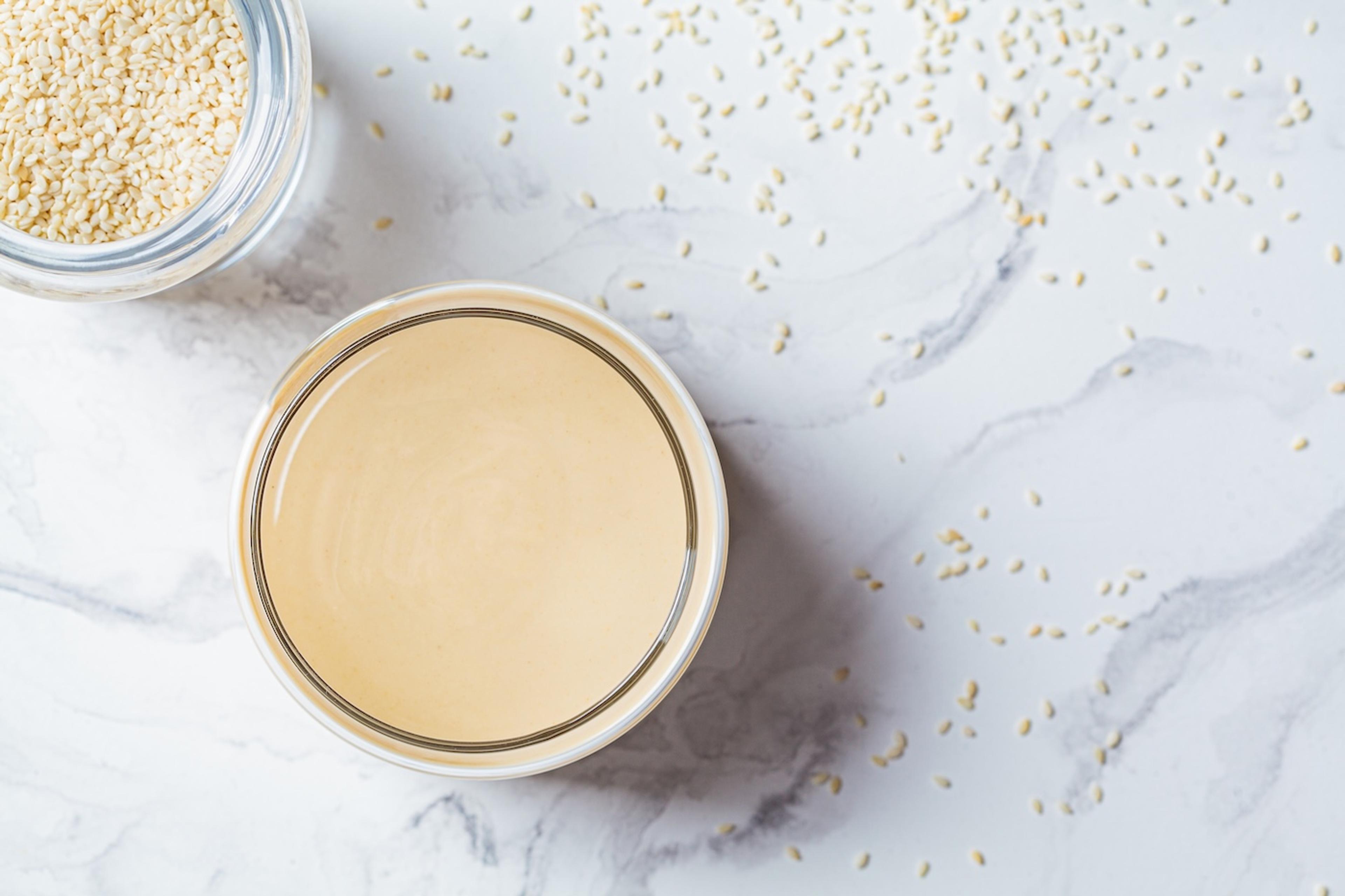 Bowl of tahini and sesame seeds on a marble table