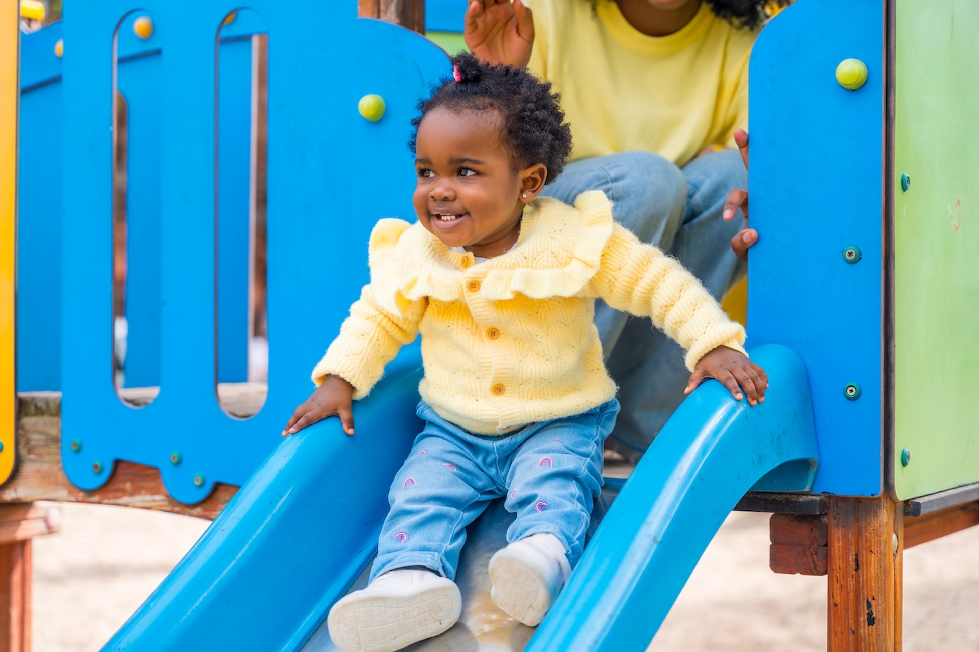 A toddler goes down the slide