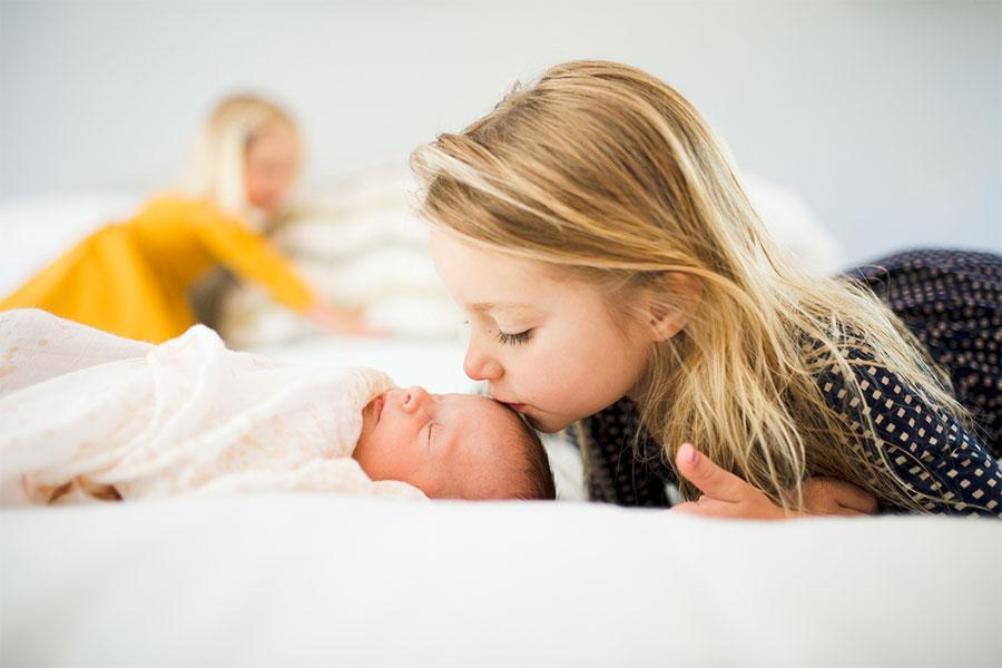 Toddler gently kissing a baby