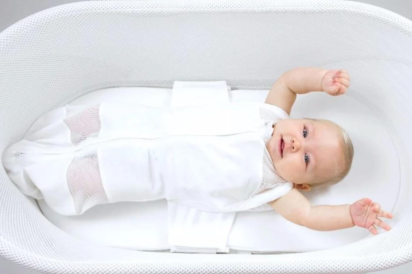 A baby sleeps in SNOO Smart Sleeper with arms out