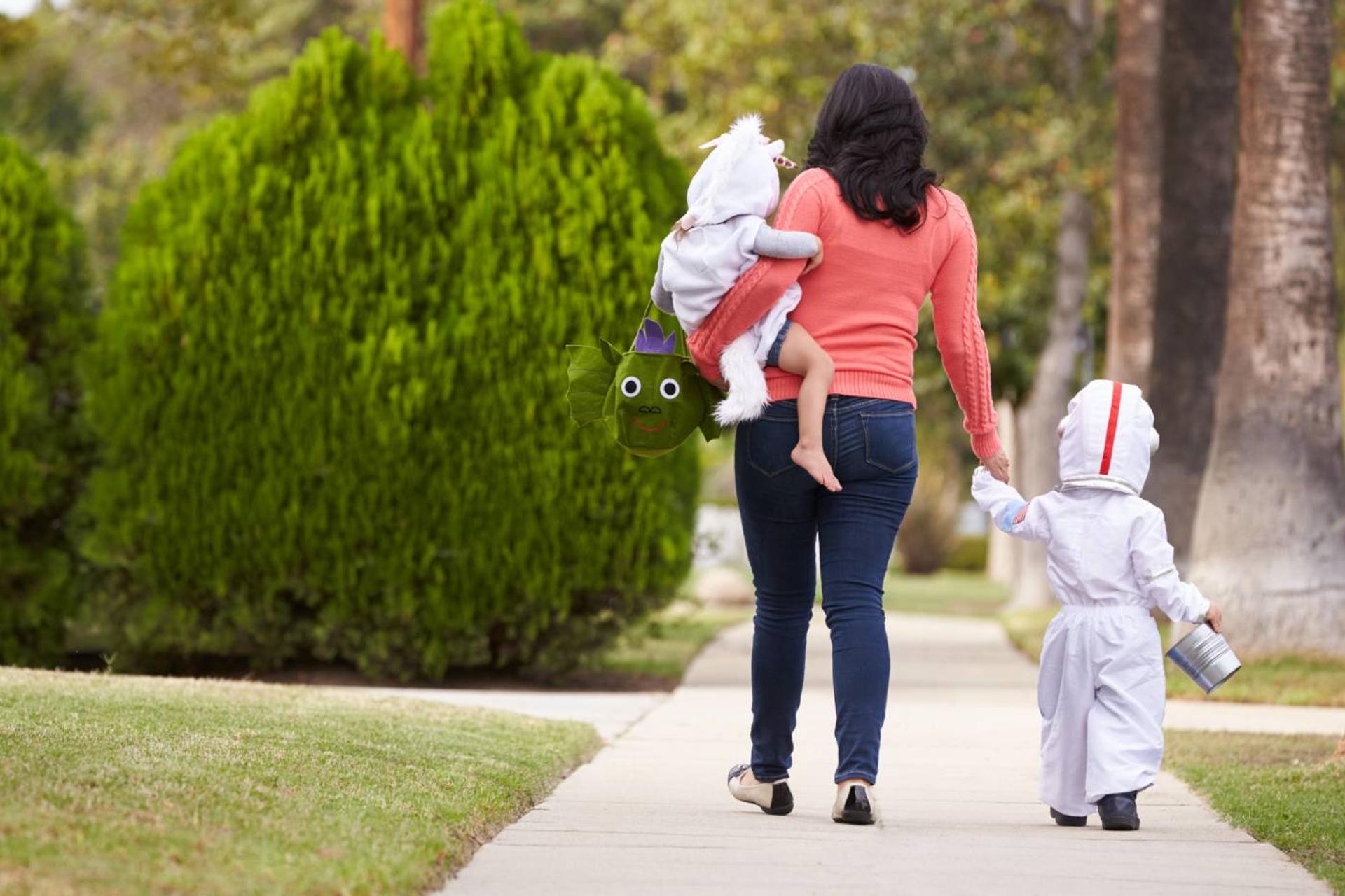 Mom trick-or-treating with baby and toddler on Halloween