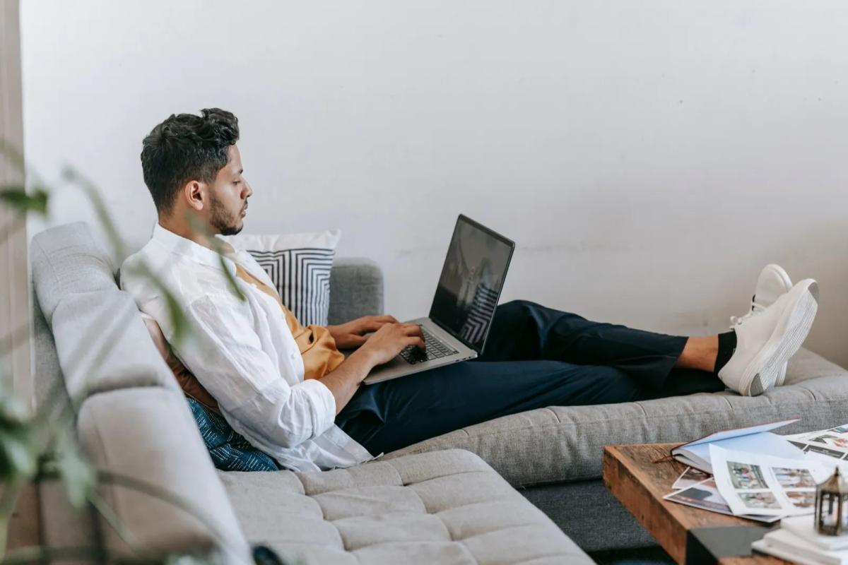 Freelance travaillant avec son ordinateur portable installé sur le canapé de son salon