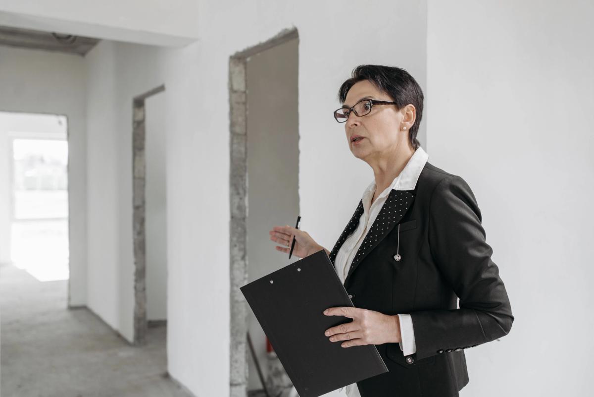 Locataire réalisant l'état des lieux d'entrée d'un appartement vide avec son smartphone
