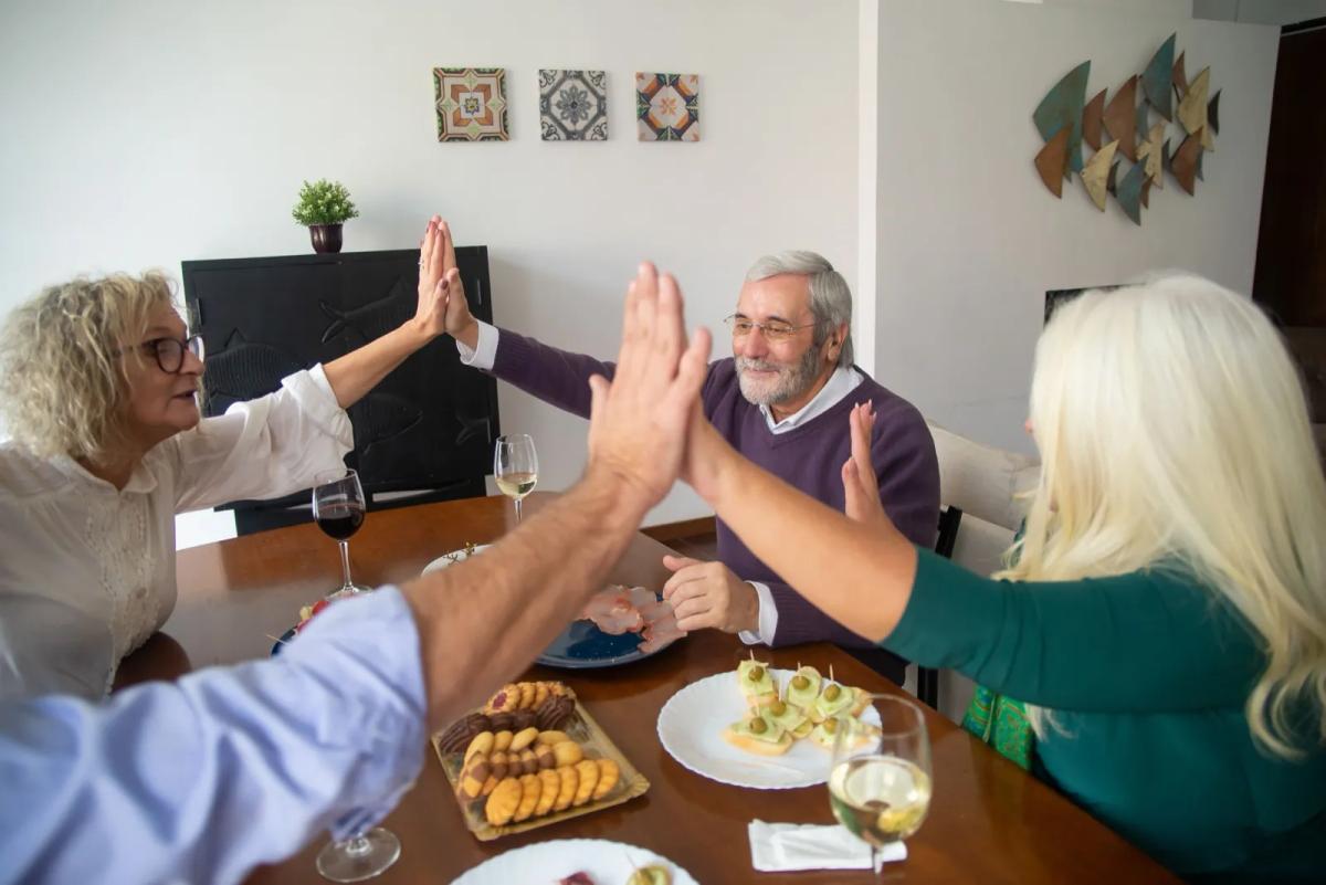 Groupe de seniors partageant un repas convivial dans la cuisine commune d'une colocation