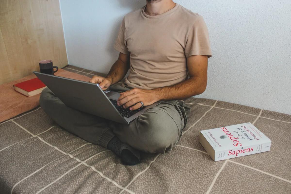 Étudiant dans son studio en train de chercher son aide au logement sur un ordinateur