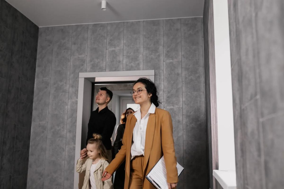 Jeune couple visitant un appartement lumineux avec un agent immobilier