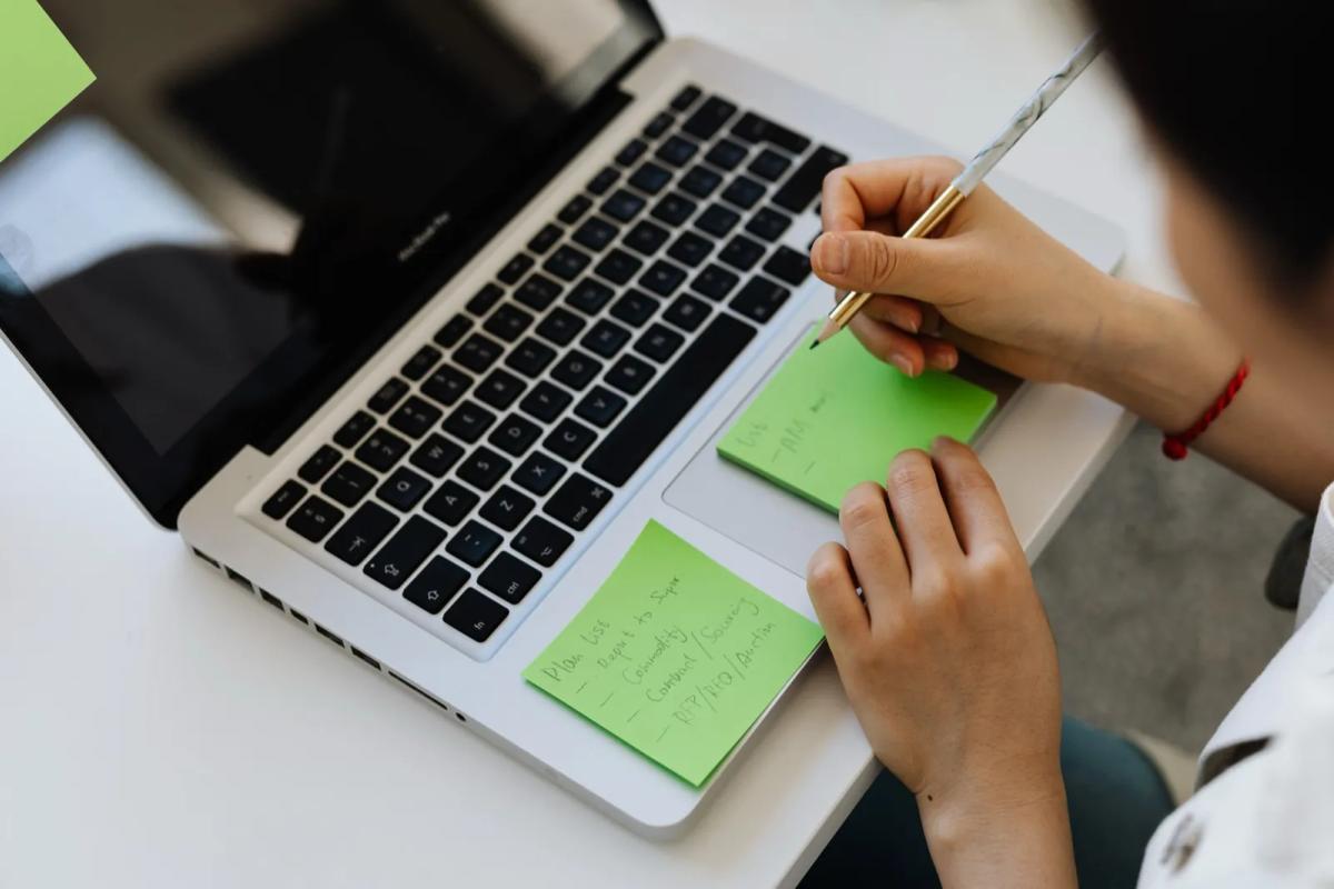 Personne organisant sa recherche de logement avec un ordinateur et des notes