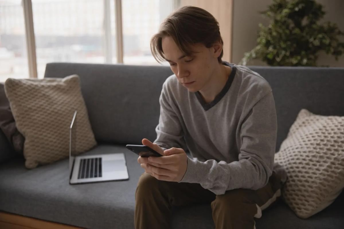 Personne consultant des annonces immobilières sur smartphone et ordinateur portable