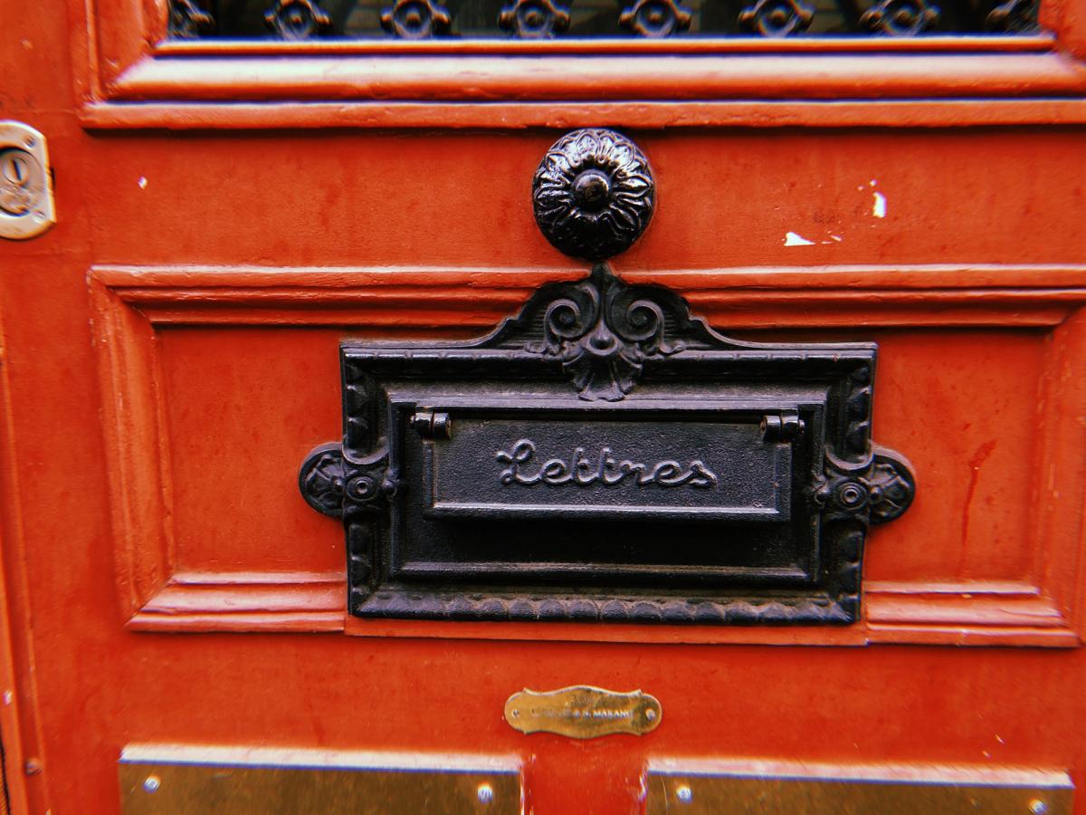 Boîte aux lettres débordant de courrier non relevé devant un logement