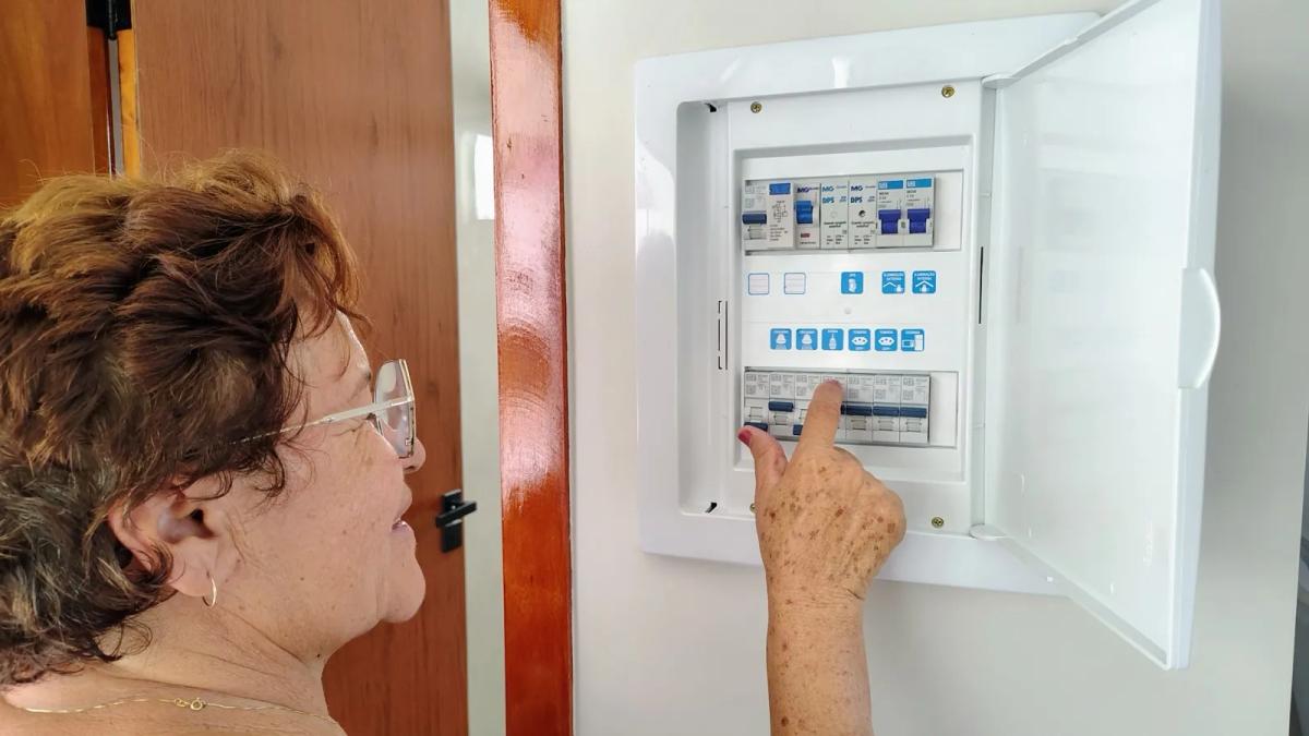 Locataire vérifiant le disjoncteur de son chauffe-eau électrique sur le tableau électrique