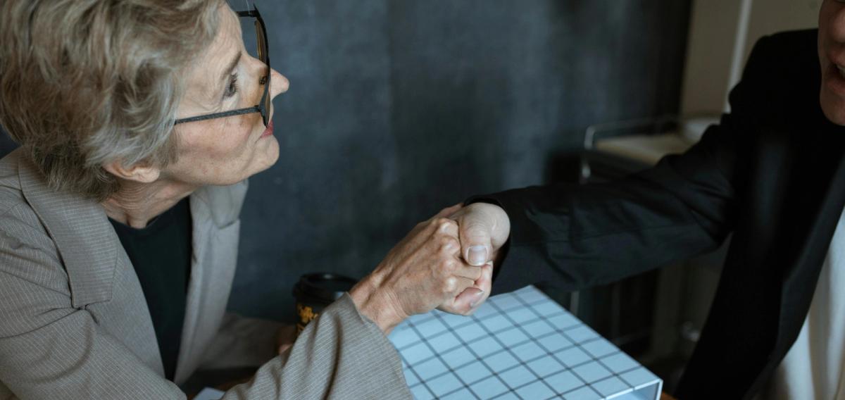 Senior souriant tenant des clés d'appartement devant une porte d'entrée